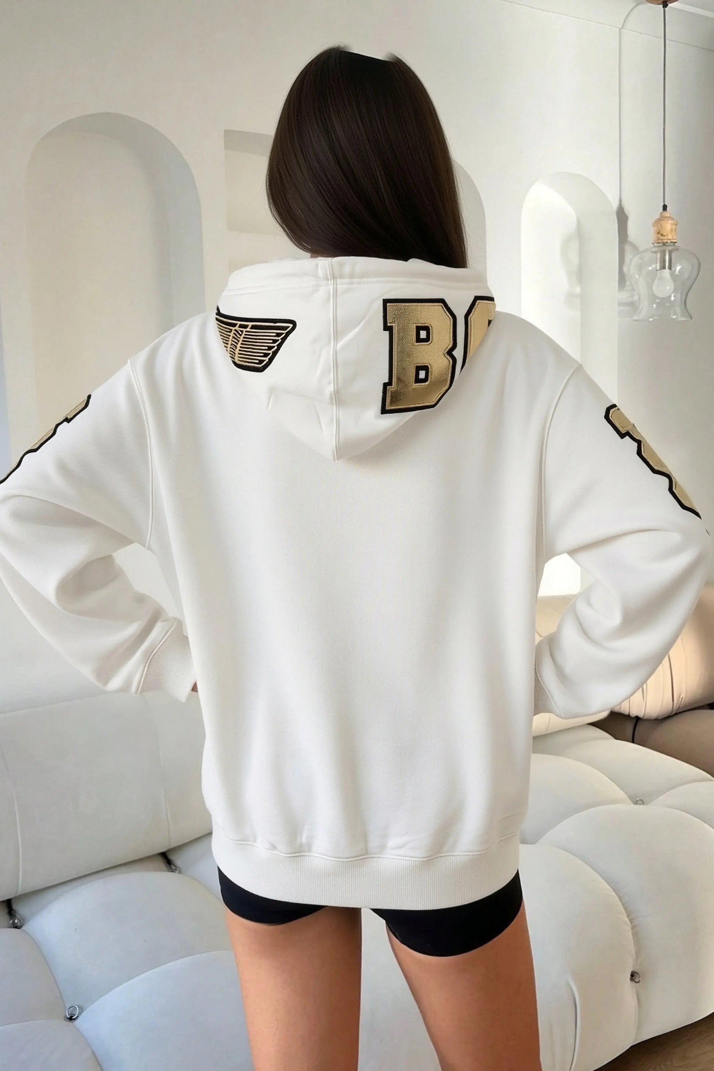 Person wearing a white hoodie with gold lettering in a modern indoor setting, TCH Rhinestone Horse Graphic Jacket