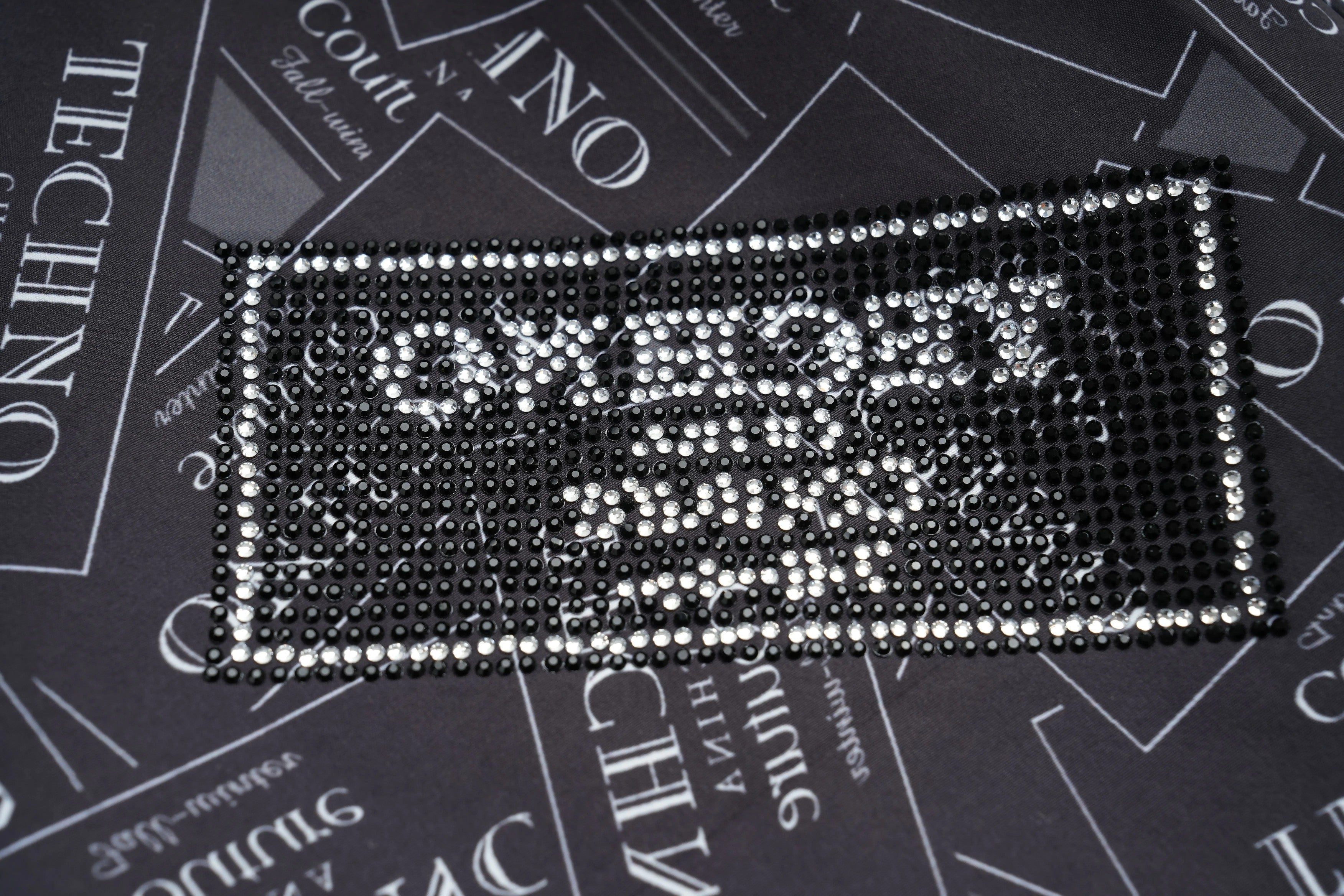 Decorative rectangular object with rhinestones on a black background with text, TCH Rhinestone Logo Patch Wide-Leg Track Pants