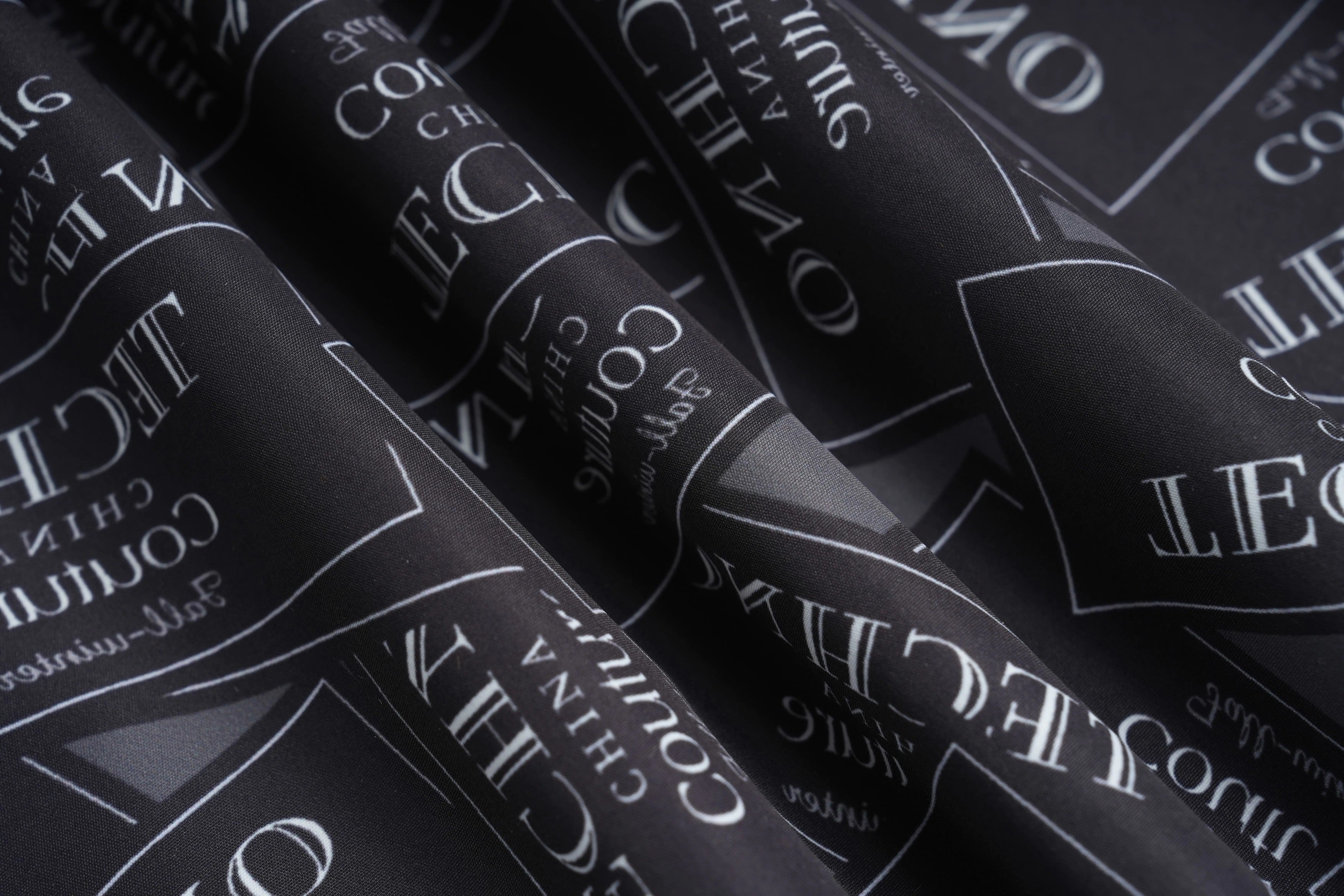 Close-up of black fabric with white text pattern, likely a brand logo. TCH Rhinestone Logo Patch Wide-Leg Track Pants