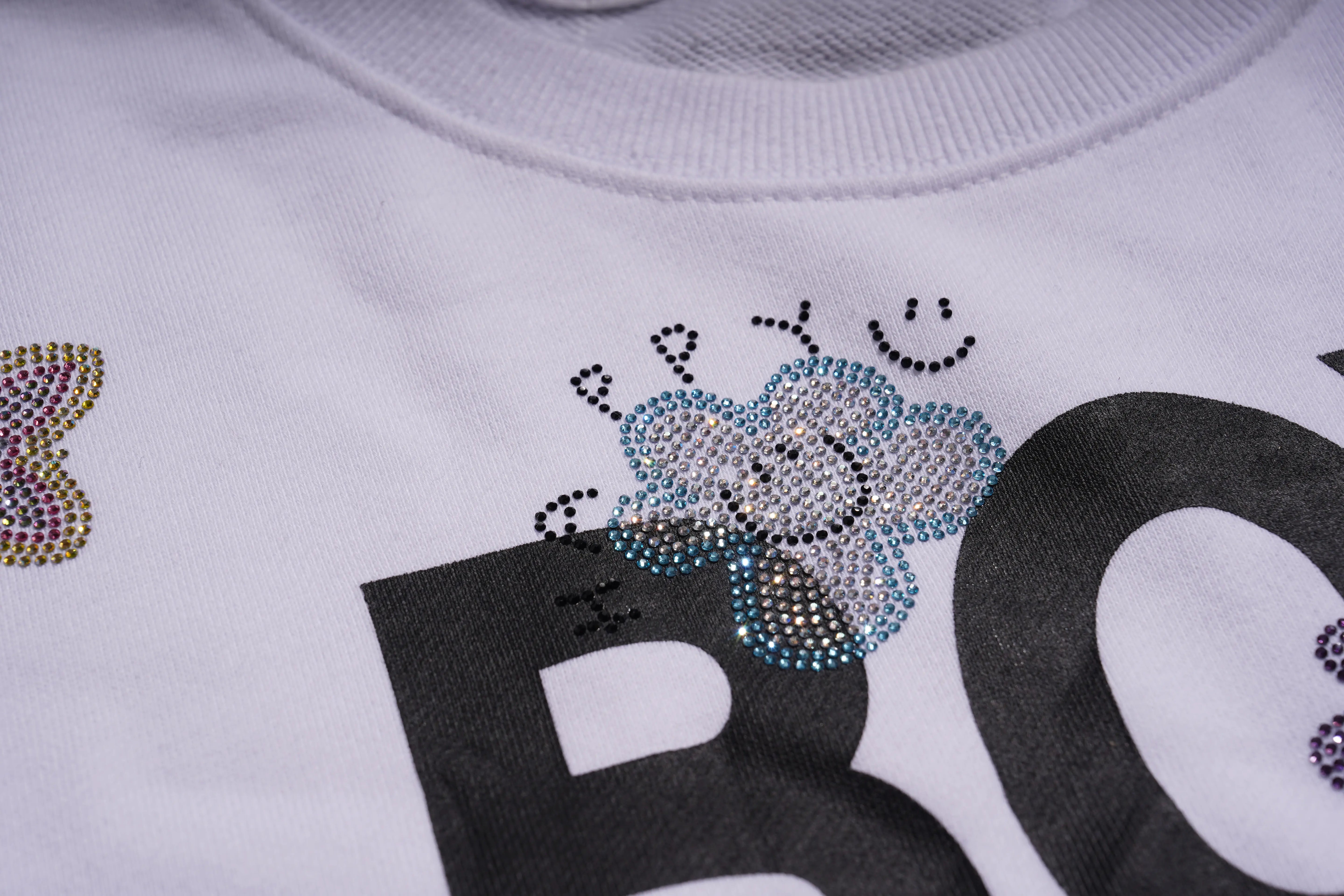 Close-up of a white sweatshirt with rhinestone decorations and text. TCH Rhinestone Logo Print Crew Neck Sweatshirt