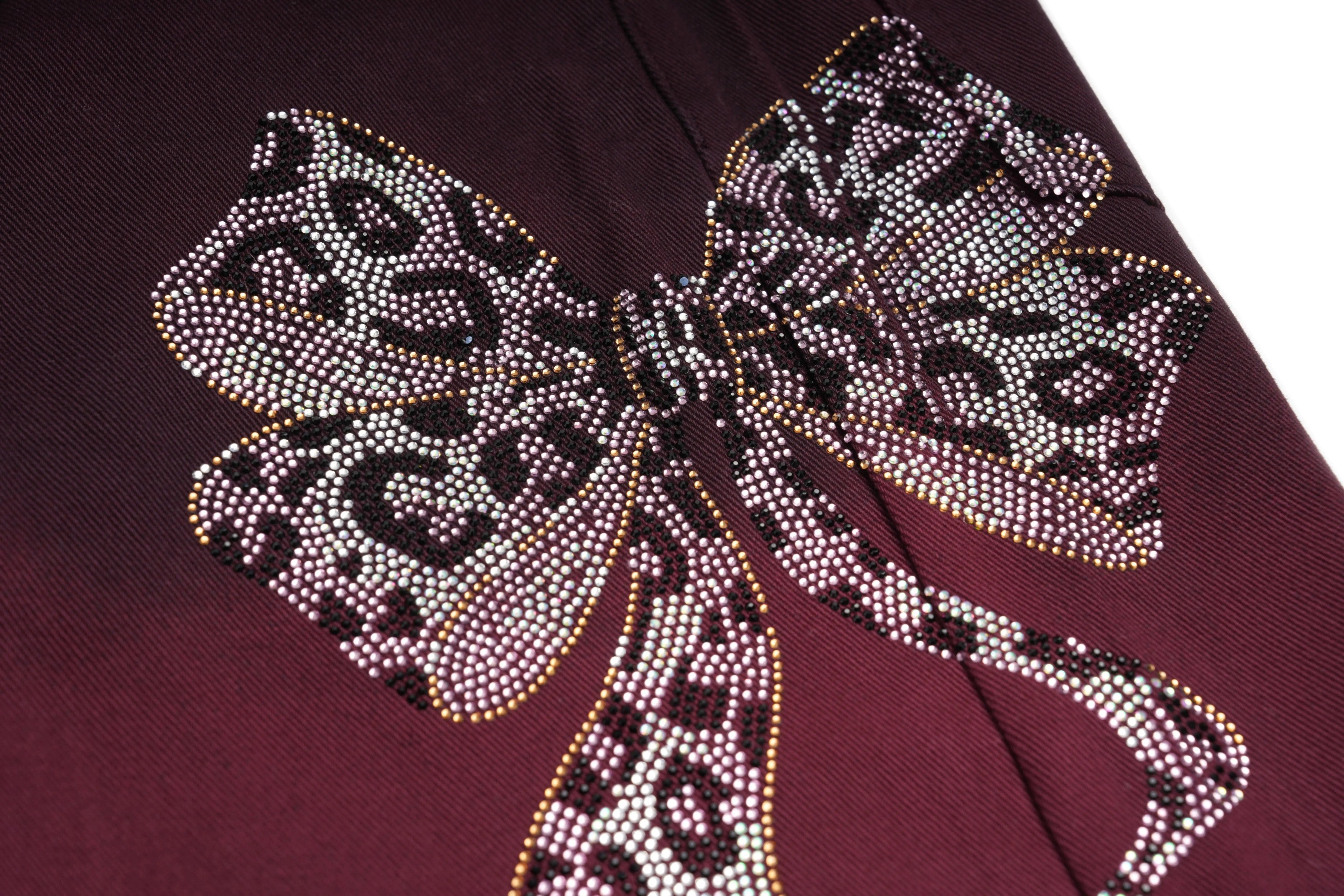 Close-up of a decorative bow with rhinestones on a maroon background, TCH Rhinestone Logo Red Denim Jeans