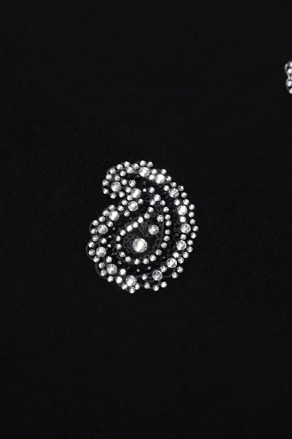 A close-up of a silver-toned embellished paisley brooch or decorative pin set with clear rhinestones on a solid black background. TCH Rhinestone Paisley Pattern Long Sleeve Polo Shirt