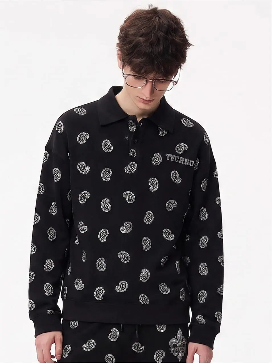A man wearing a black long-sleeve polo sweatshirt with a white paisley pattern and 'TECHNO' text on the chest, paired with matching pants, against a plain white background. TCH Rhinestone Paisley Pattern Long Sleeve Polo Shirt