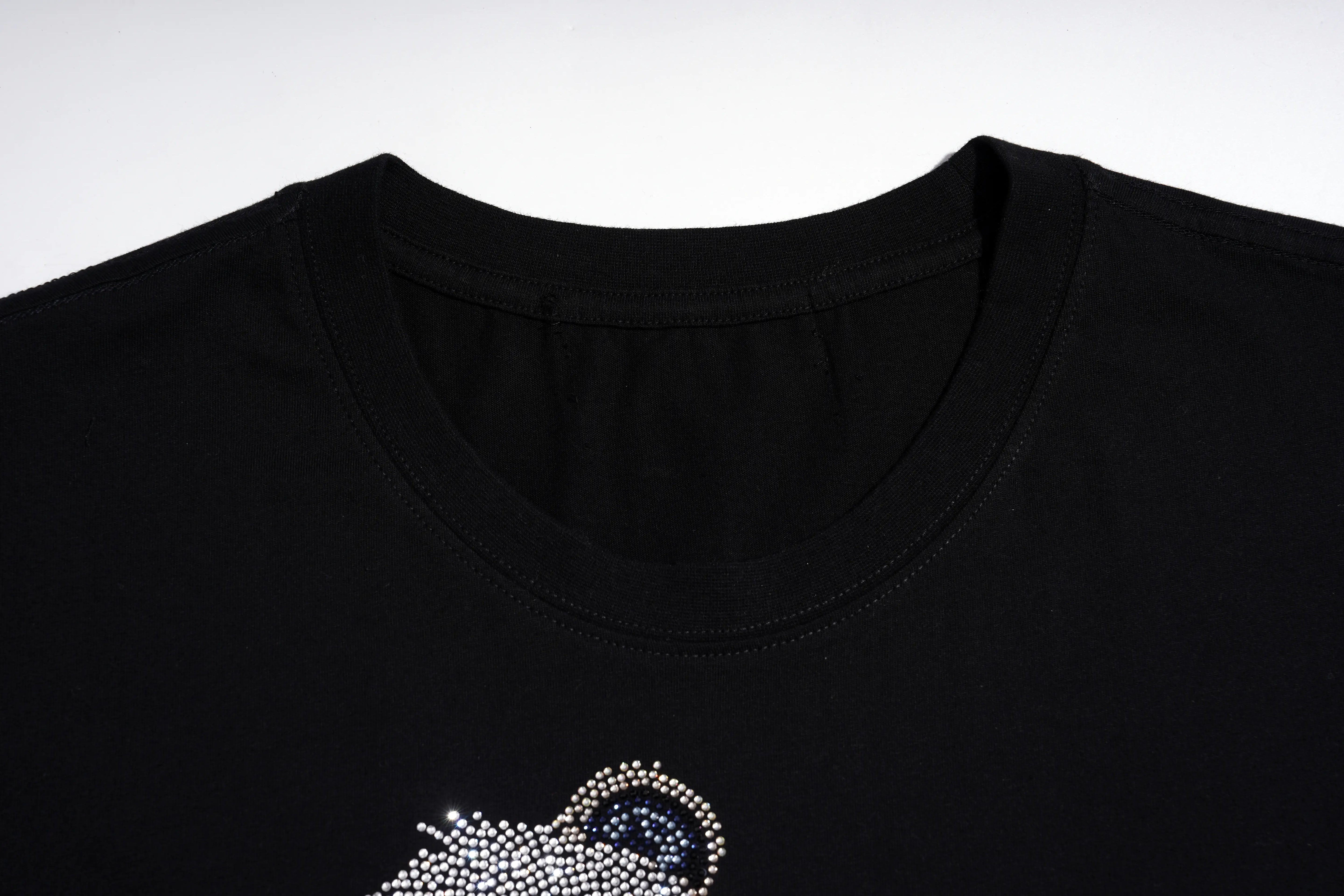 Close-up of a black crewneck t-shirt featuring a rhinestone-embellished astronaut graphic on the lower left chest. TCH Rhinestone Panda Graphic Sleeveless T-Shirt