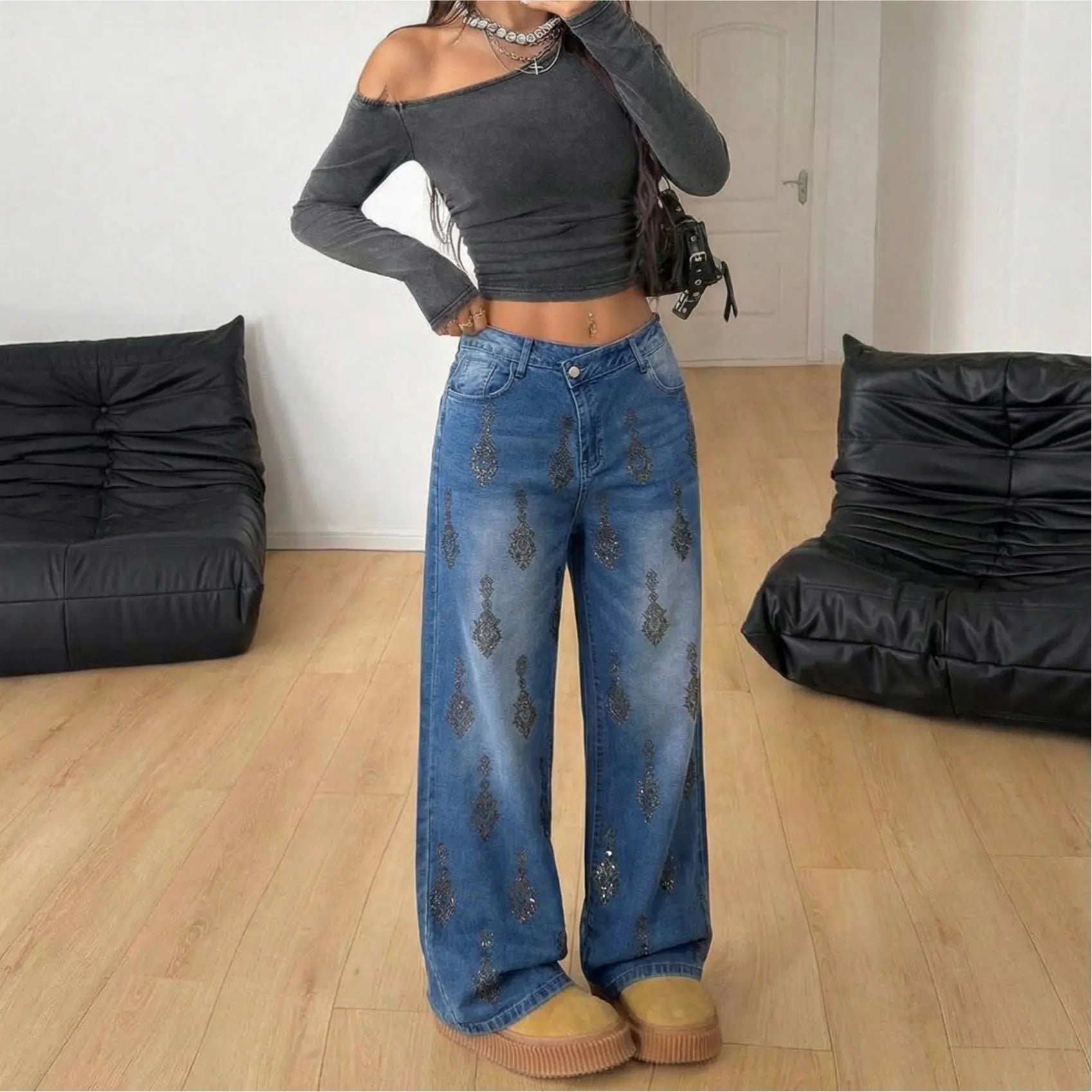 Person wearing a gray off-shoulder top and blue jeans in a room with black bean bags. TCH Rhinestone Pendant Allover Denim Jeans