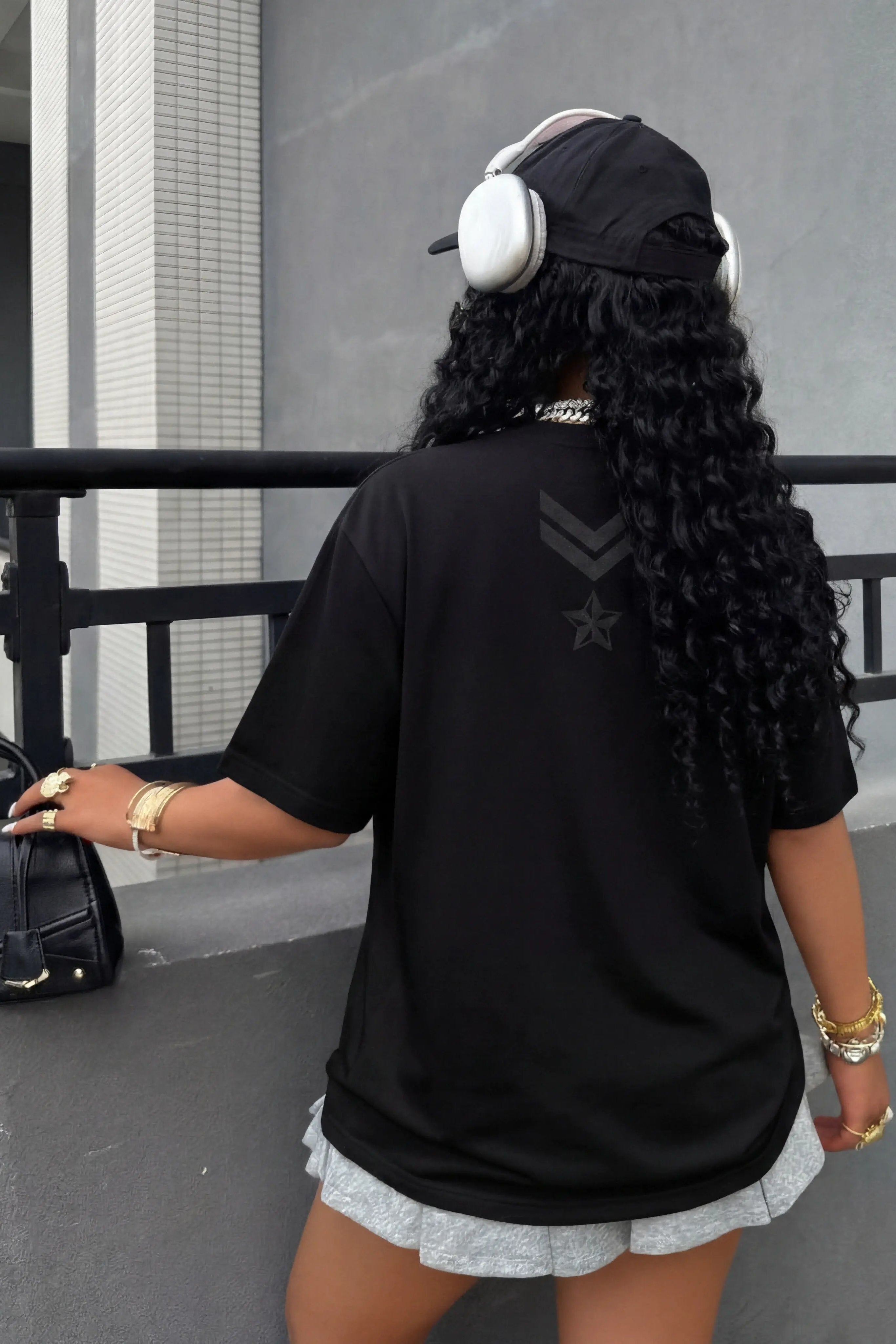 Person wearing a black t-shirt with a star design, white shorts, and headphones, standing on a ledge. TCH Rhinestone Pink Teddy Bear T-Shirt