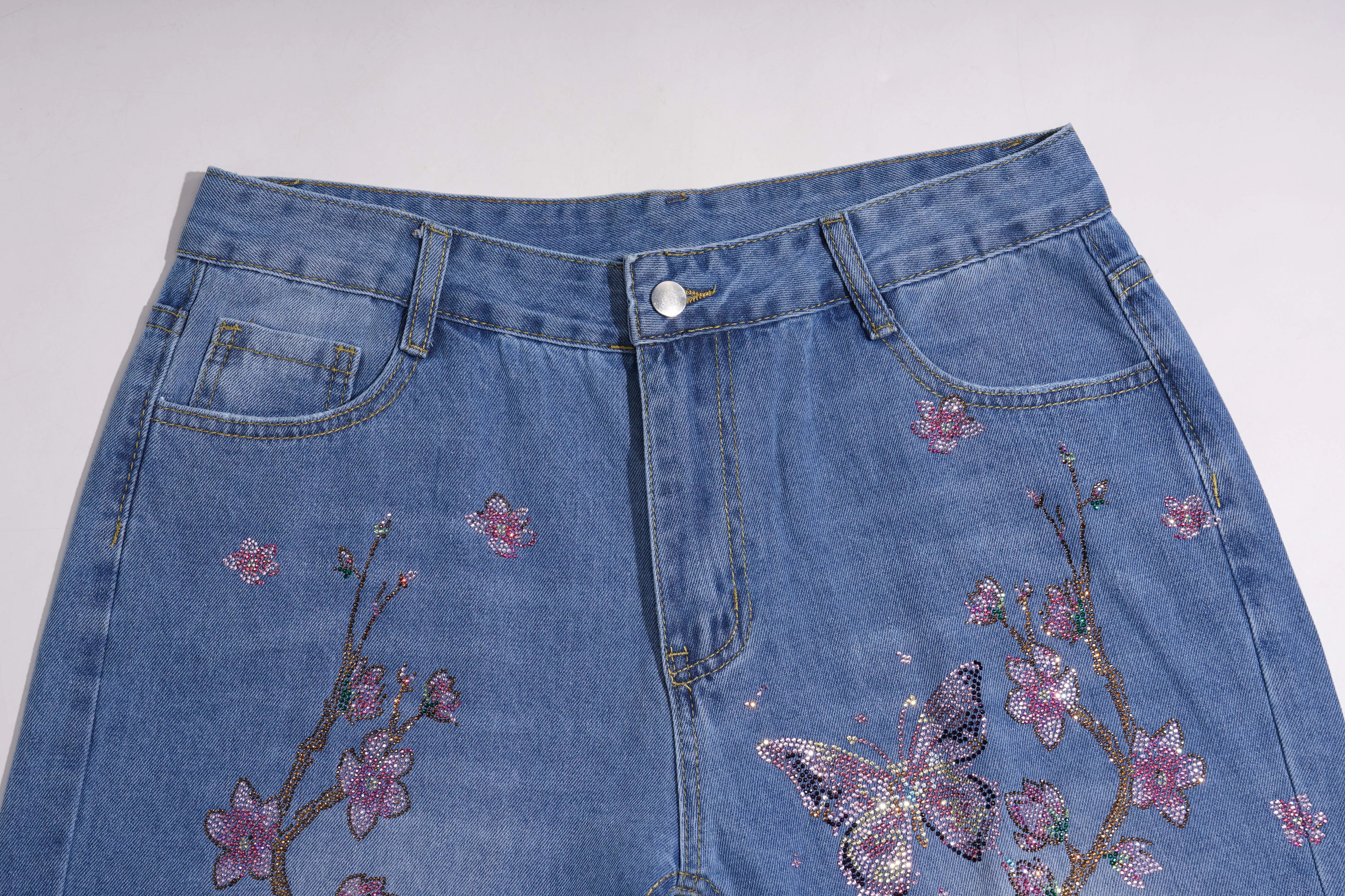 Blue denim skirt with floral and butterfly embroidery on a white background, TCH Rhinestone Plum Blossom Tree Distressed Denim Jeans