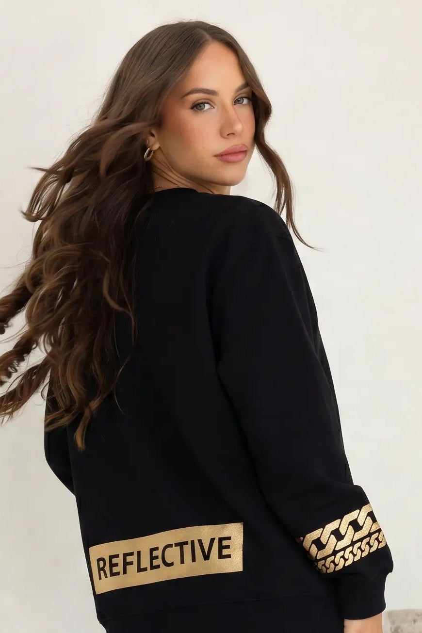 Woman wearing a black sweater with reflective text and gold accents on a plain background, TCH Rhinestone Puppy Black Streetwear Sweatshirt