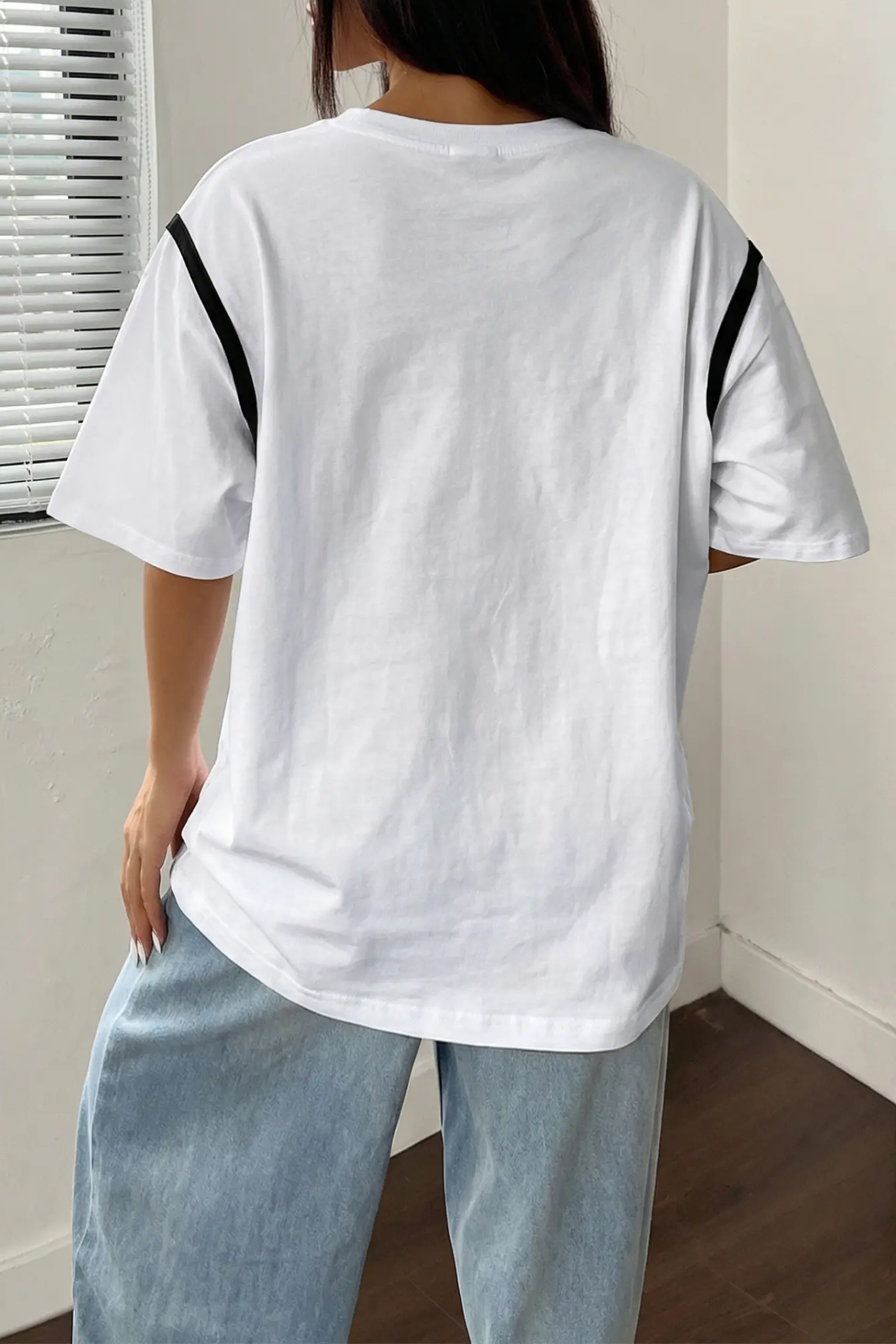Person wearing a white t-shirt with black stripes on the sleeves and light blue pants indoors. TCH Rhinestone Puppy Bow White T-Shirt-1 8
