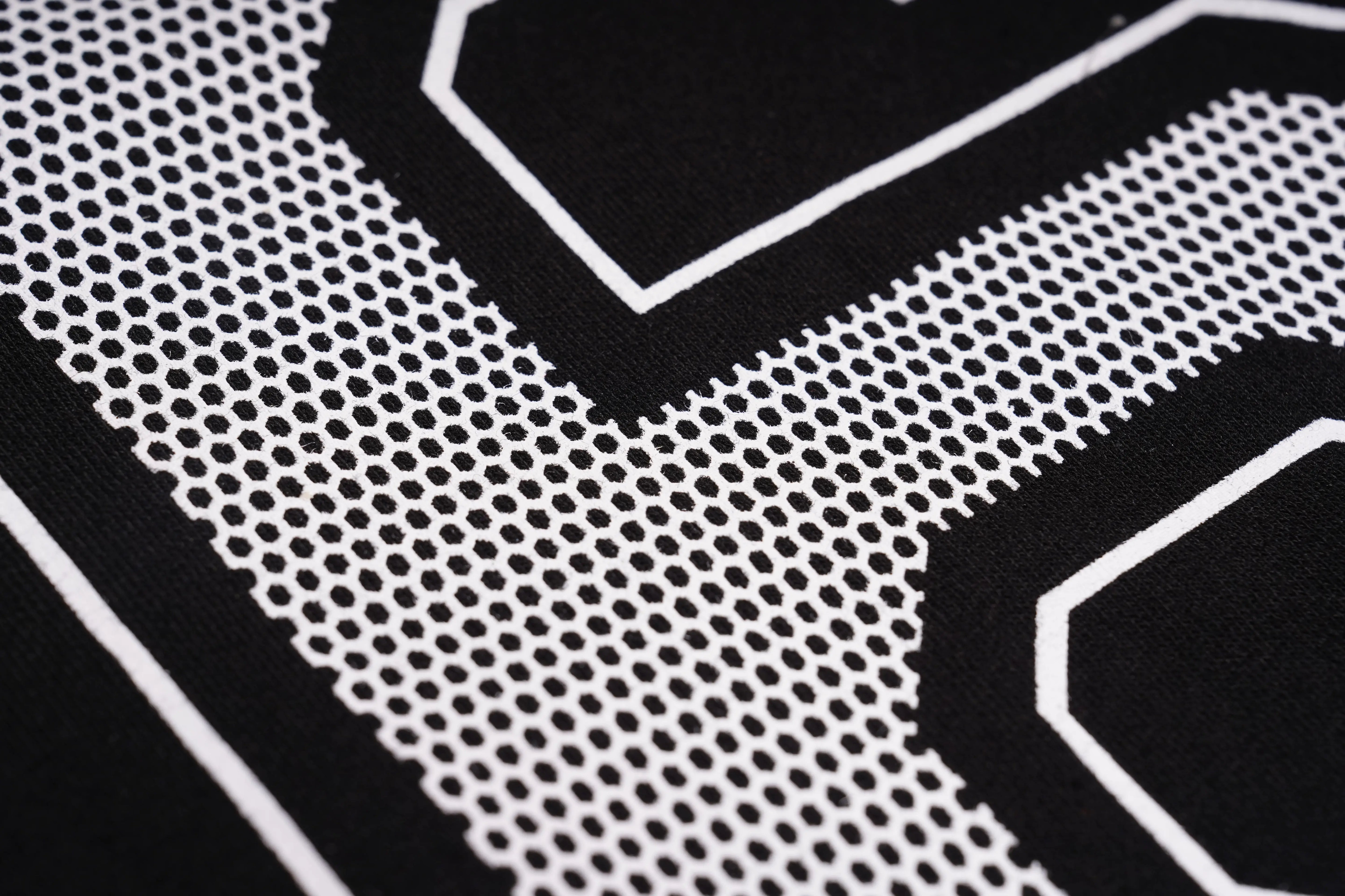 Close-up of a black and white patterned surface with geometric shapes. TCH Rhinestone Rabbit Black Red Jersey
