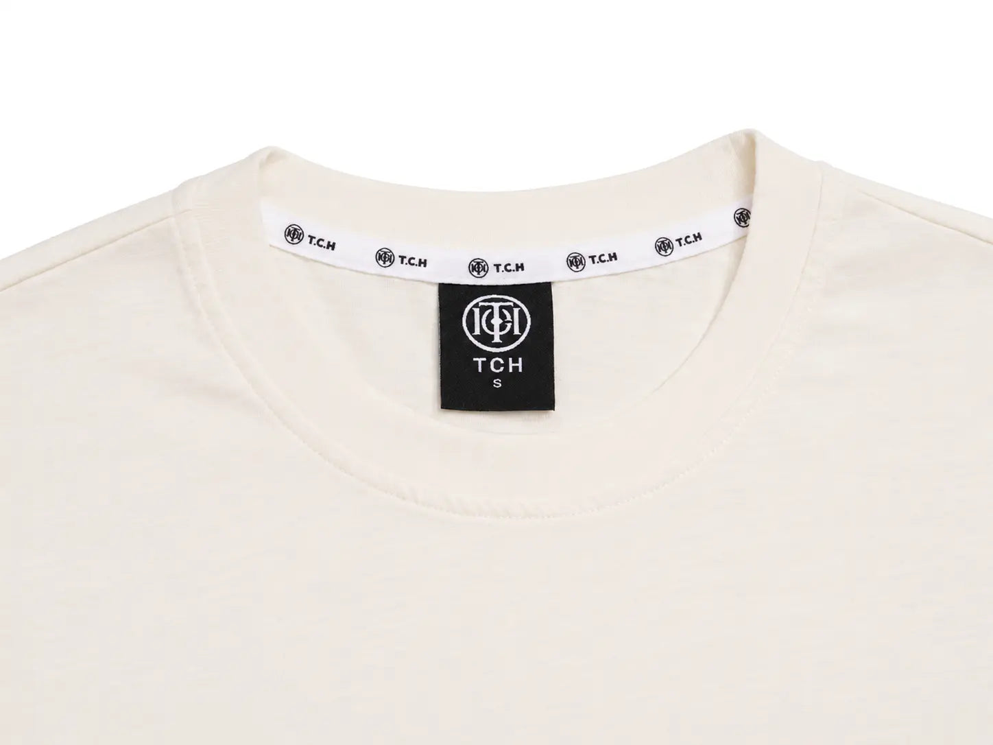 Close-up of the neckline of an off-white crewneck t-shirt, showing a black neck label with the TCH logo and a white inner collar band with repeating black TCH logos. TCH Rhinestone Sparkle Crystal Graphic White T-Shirt