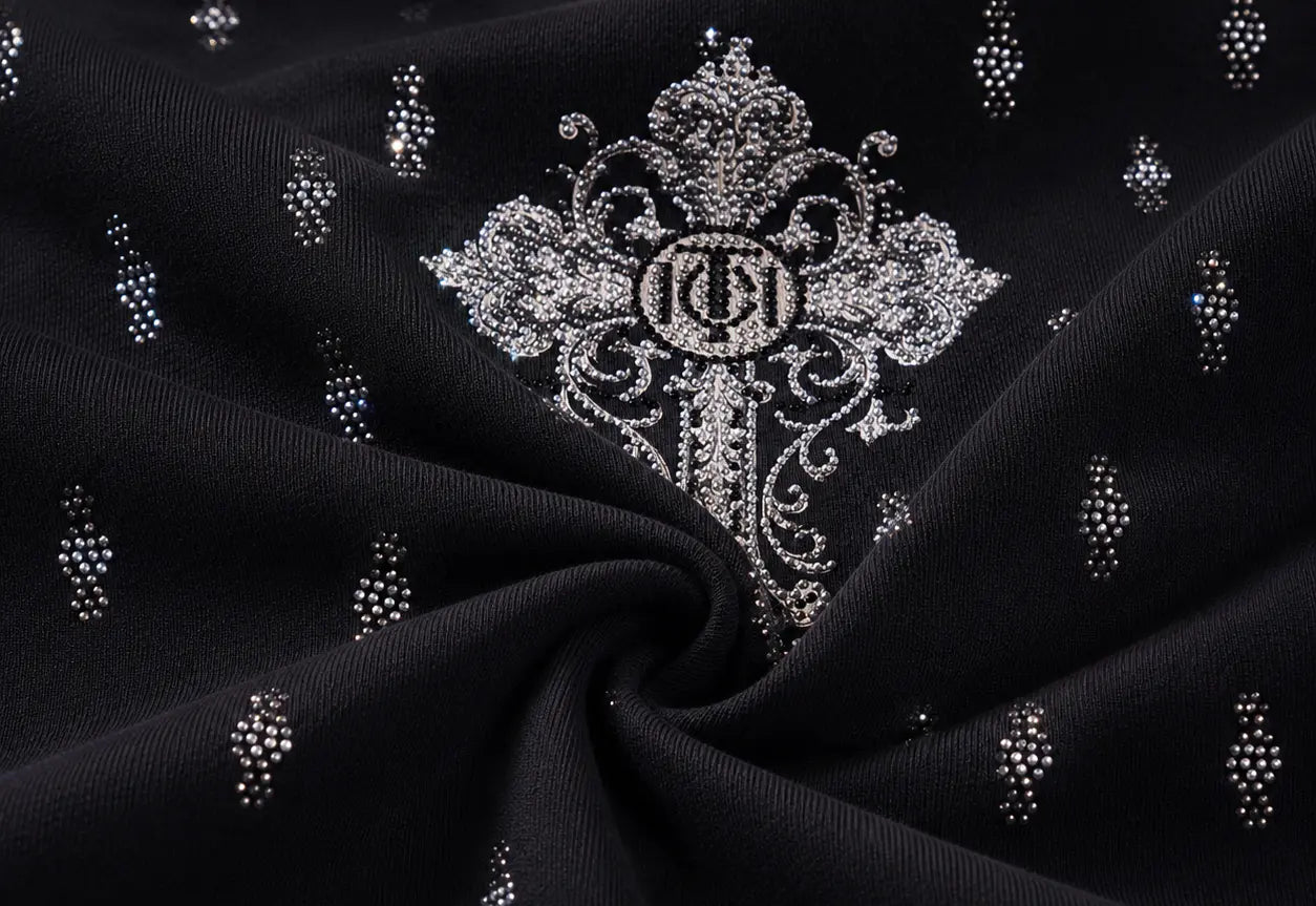 Black fabric with a large silver embroidered monogram motif in the center and small scattered silver rhinestone dot clusters, shown in a draped studio-style close-up. TCH Rhinestone Techno Cross Graphic Black T-Shirt
