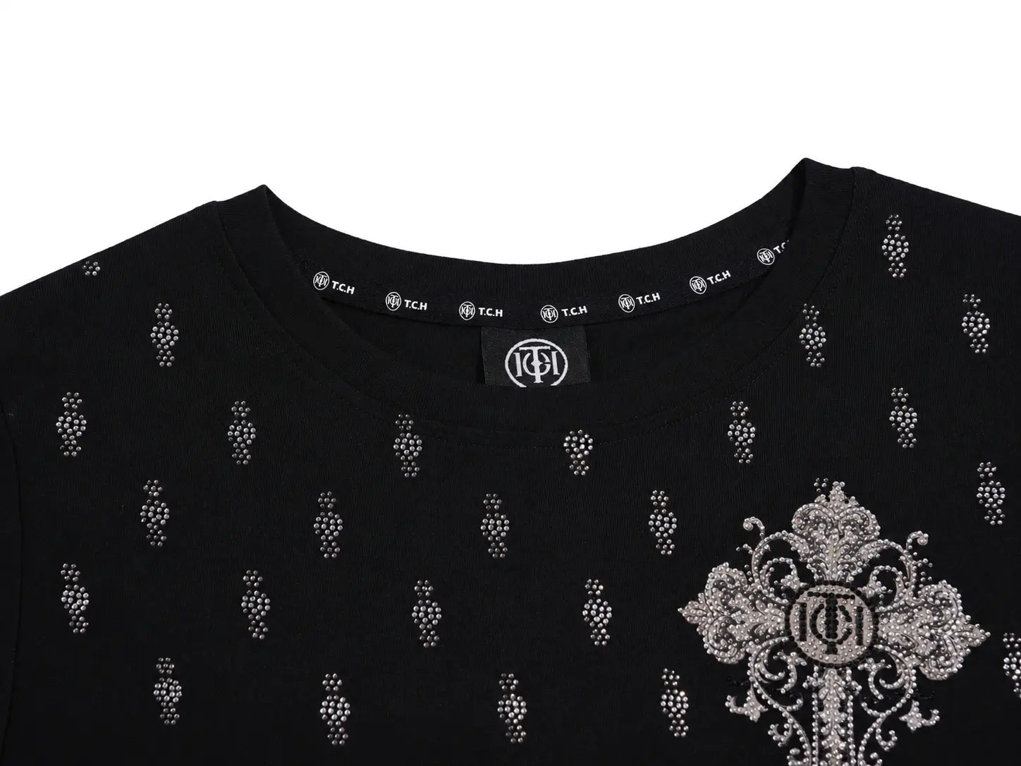 Close-up of a black crewneck T-shirt with rhinestone embellishments, featuring a repeating small motif and a large ornate cross-like emblem on the right chest with a central monogram logo. TCH Rhinestone Techno Cross Graphic Black T-Shirt