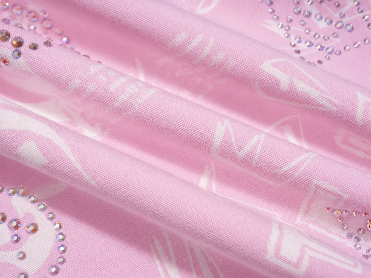 Pink fabric with a white abstract pattern and rhinestone embellishments, shown in a close-up folded view. TCH Rhinestone Techno Graphic Wide-Leg Sweatpants