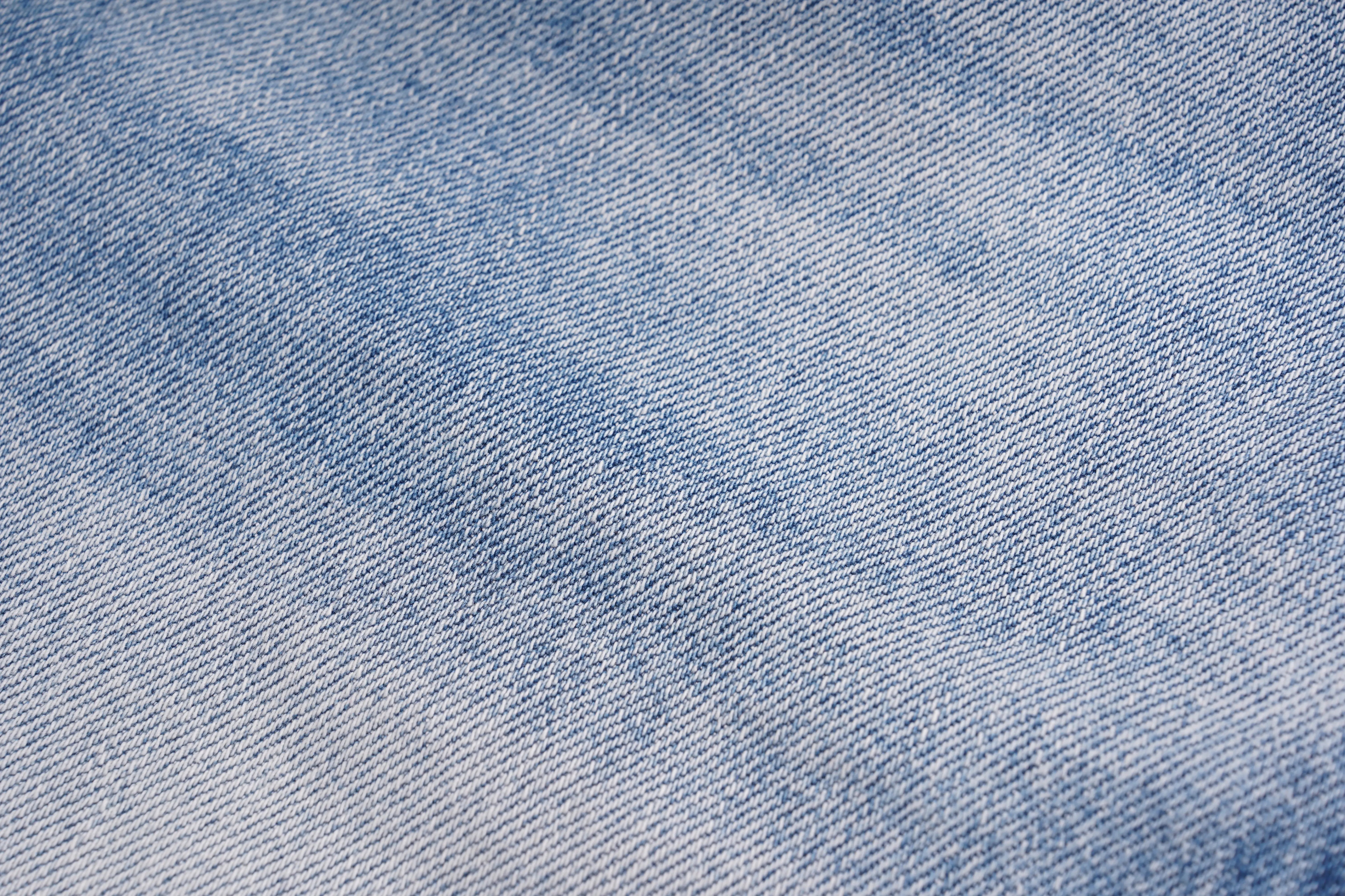 A close-up texture shot of light blue denim fabric with a subtle diagonal faded wash. TCH Rhinestone Teddy Bear Bow Denim Shorts