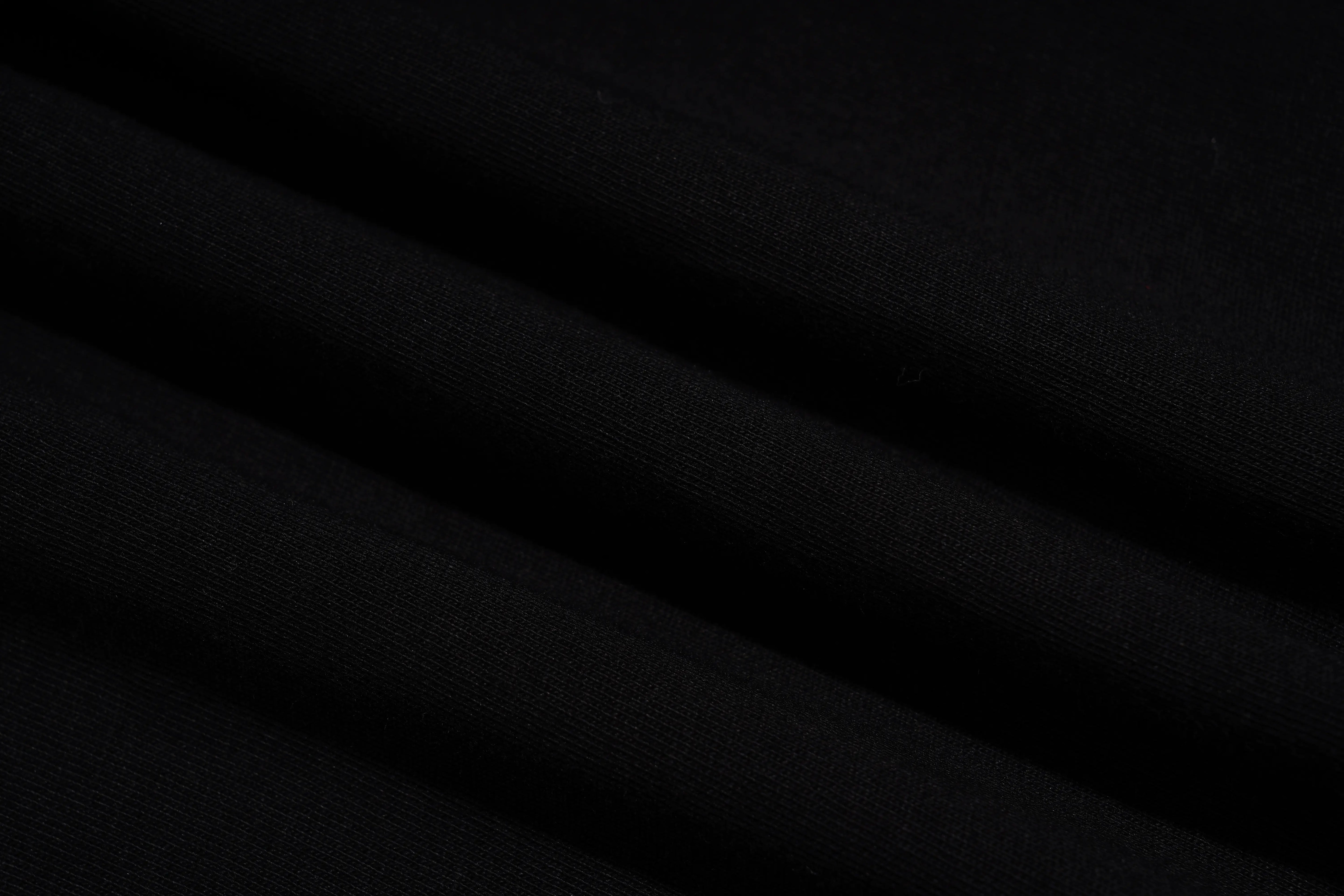 A close-up of black fabric with soft diagonal folds and a smooth matte texture. TCH Rhinestone Teddy Bear Bow Graphic Oversized Black T-Shirt