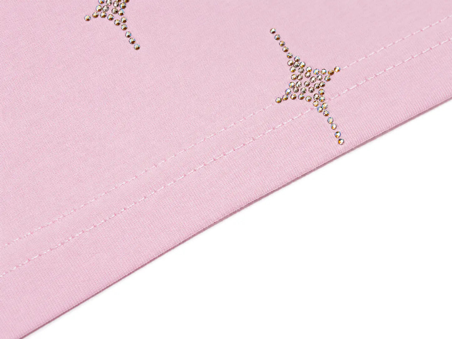 Close-up of a light pink fabric surface with two small rhinestone star embellishments and a stitched seam running diagonally, set against a white background. TCH Rhinestone Teddy Bear Bow Pink Graphic T-Shirt