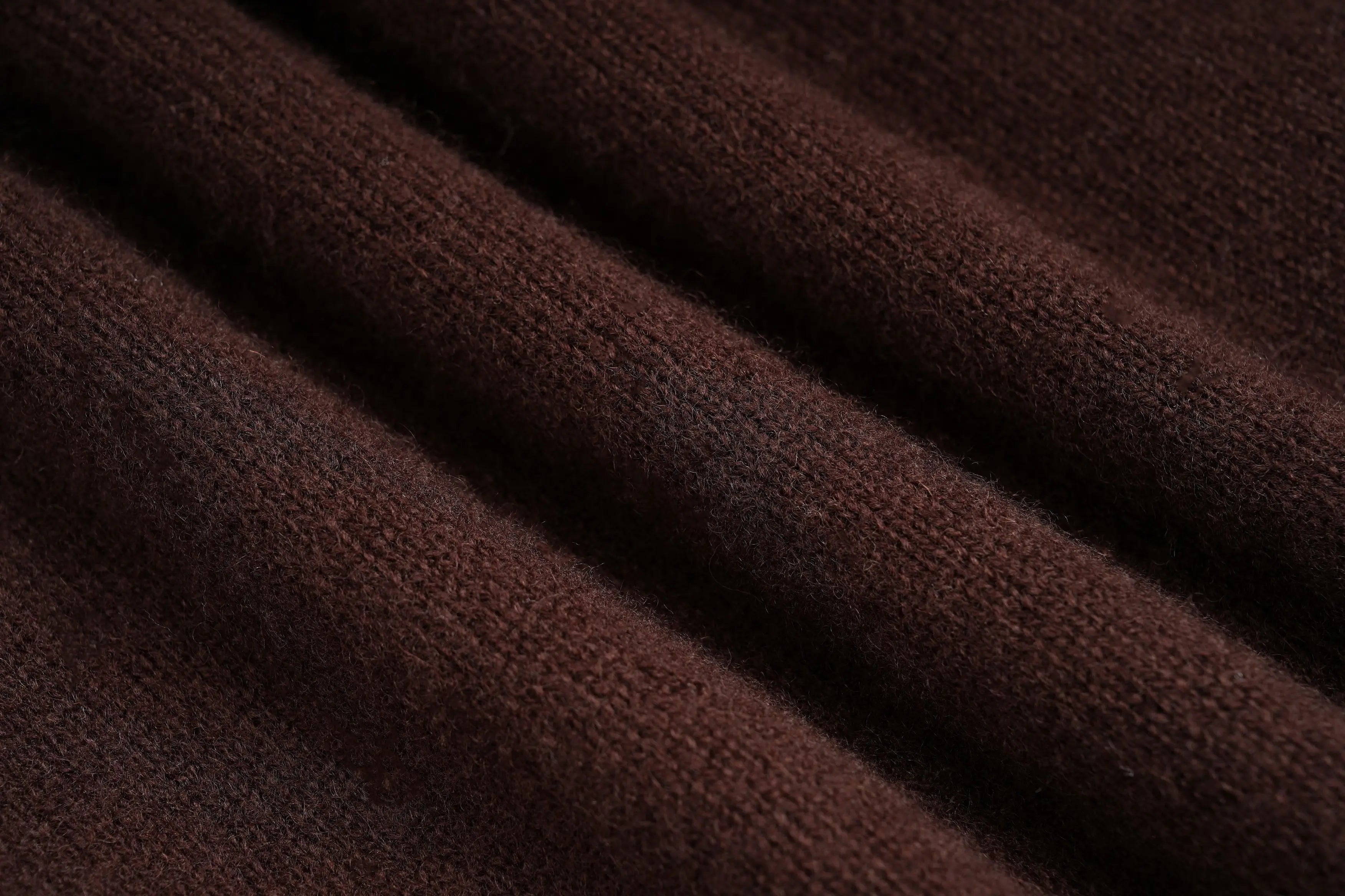 A close-up of dark brown ribbed knit fabric with soft folds and a plush texture. TCH Rhinestone Teddy Bear Bow Ruffle Knit Cardigan
