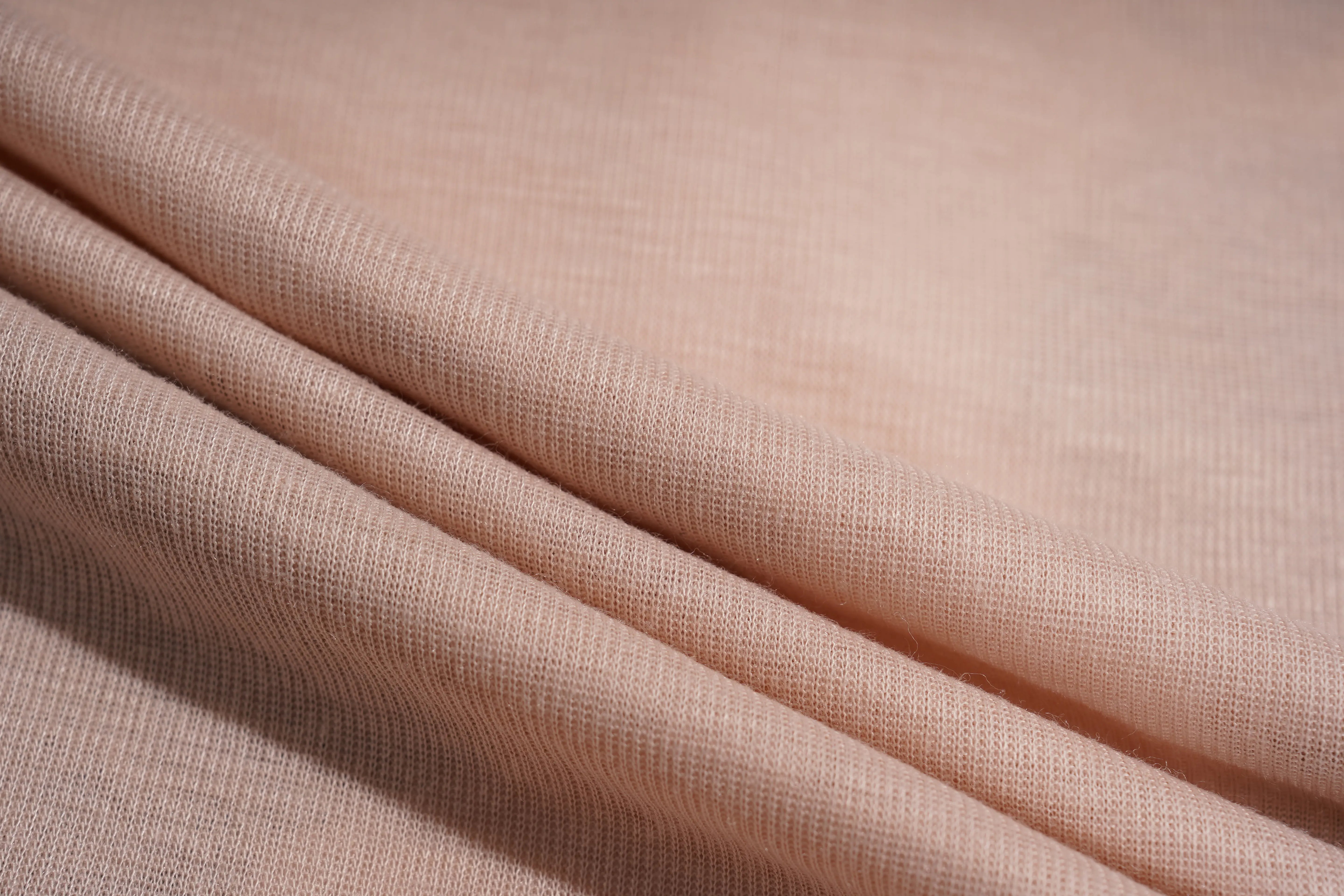 A close-up of draped woven fabric in a soft blush pink color, showing the texture and folds. TCH Rhinestone Teddy Bear Bow Ruffle Long Sleeve Top