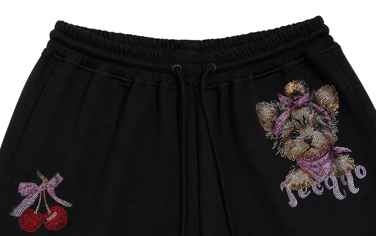 Black sweatpants featuring a sparkling rhinestone teddy bear graphic on the right leg and a rhinestone cherry graphic on the left leg, with a drawstring waistband. TCH Rhinestone Teddy Bear Cherry Graphic Sweat Shorts
