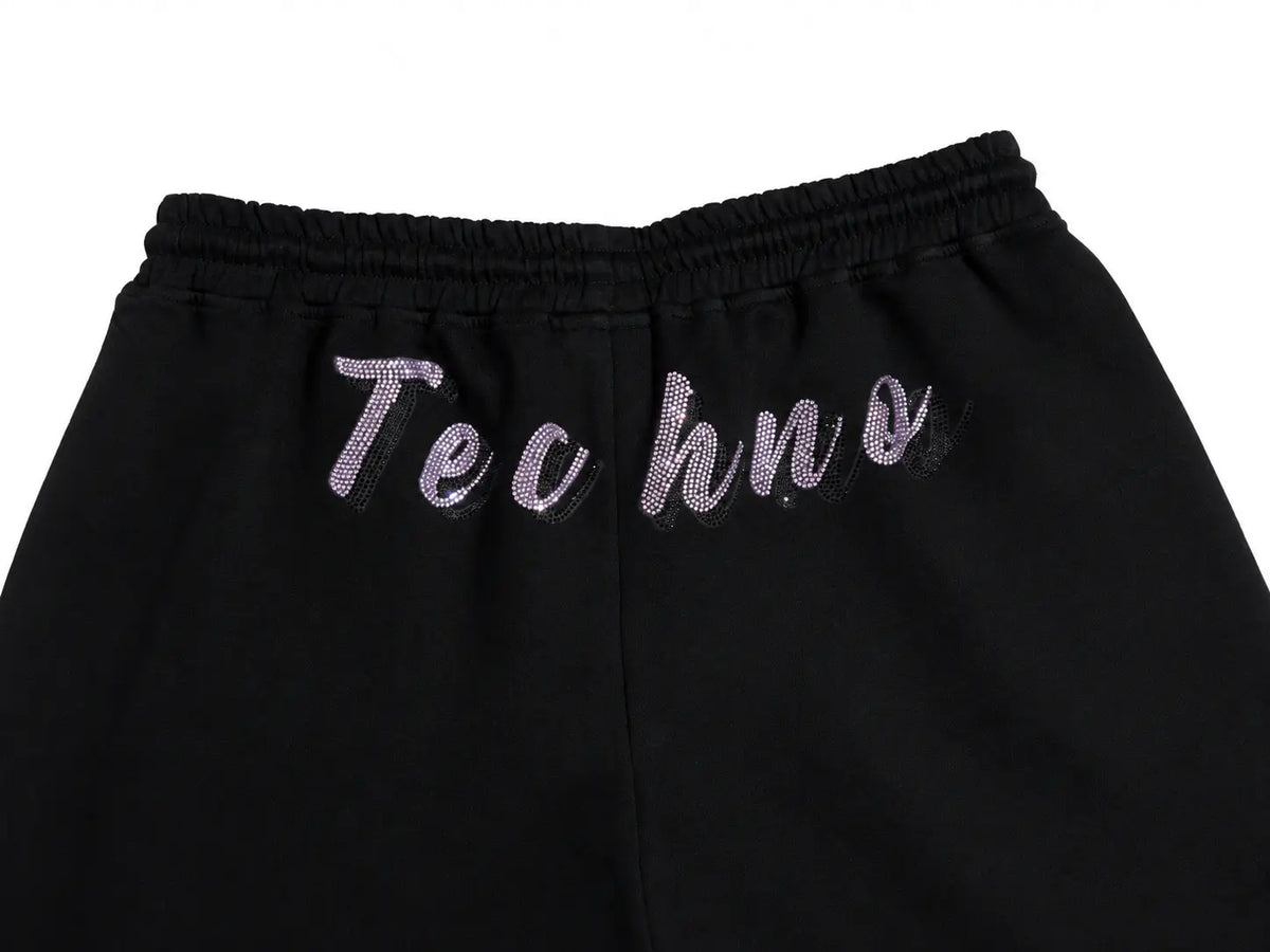 Close-up of black sweatpants with an elastic waistband and the word 'Techno' in a glittery light purple script across the back, shown against a plain white background. TCH Rhinestone Teddy Bear Cherry Graphic Sweat Shorts