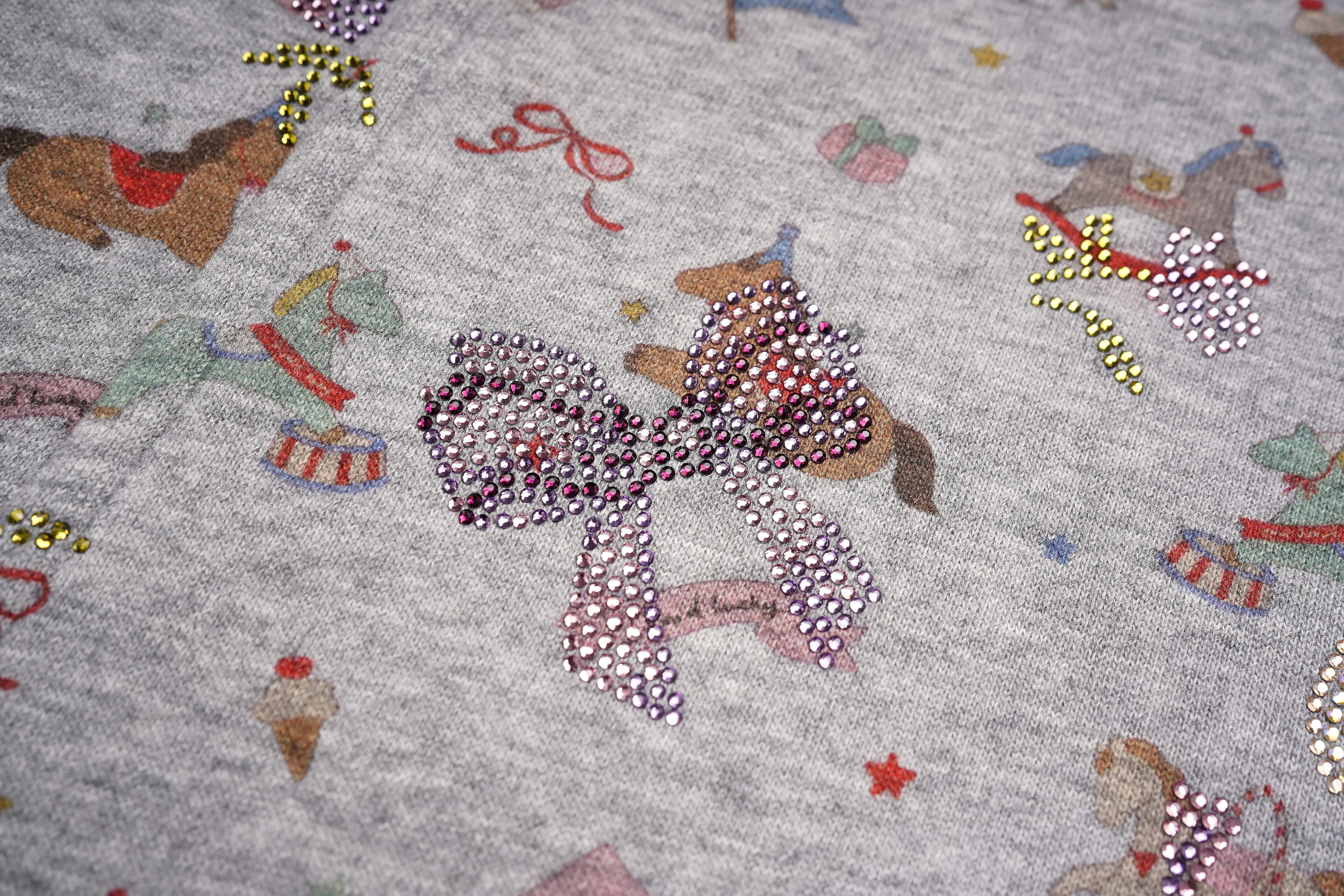 Fabric with decorative elements including a large bow and small illustrations on a gray background. TCH Rhinestone Teddy Bear Grey Printed Pants