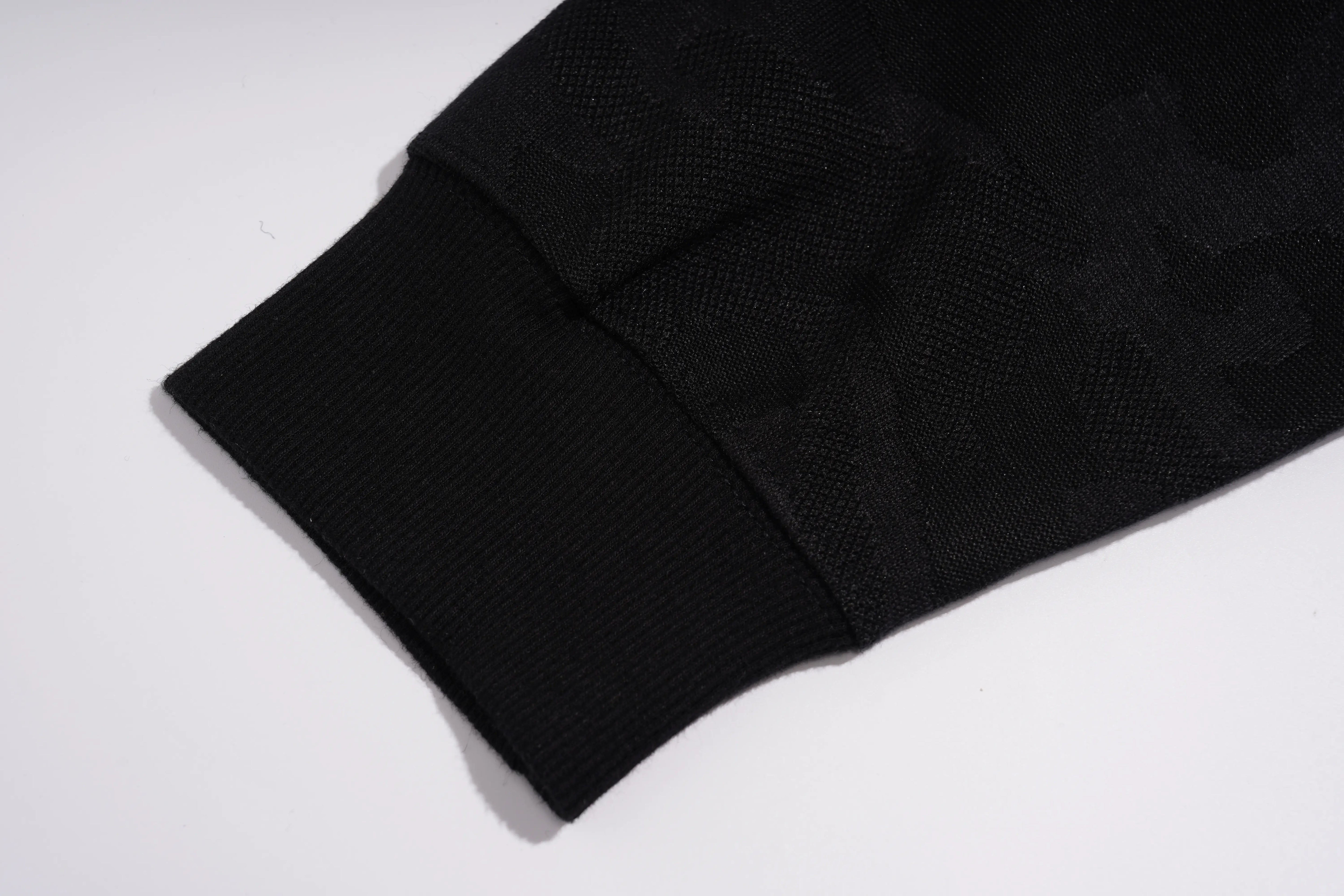 Close-up of a black ribbed knit cuff on a black textured garment, photographed on a plain white background. TCH Rhinestone Teddy Bear Pearl Chain Graphic Sweatshirt