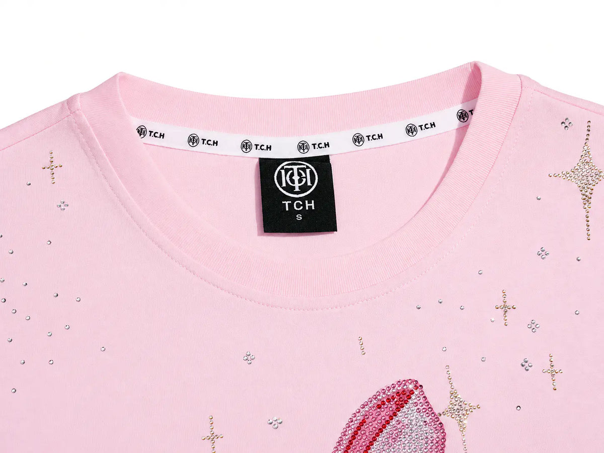 Close-up of a light pink TCH crewneck top featuring rhinestone star and cross embellishments, with a black neck label and white inner collar band. TCH Rhinestone Teddy Bear Pink Long Sleeve T-Shirt