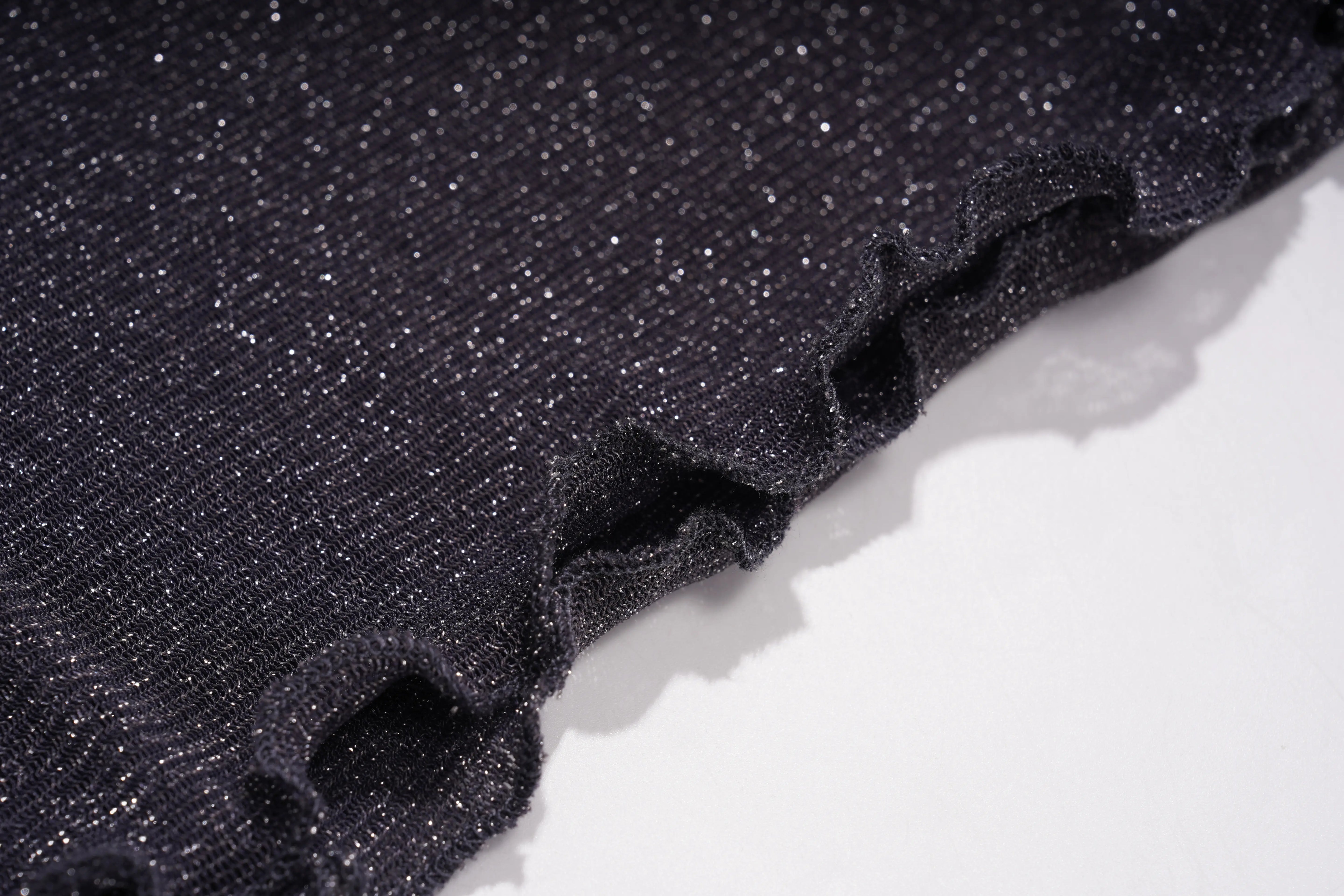 A close-up of a black glittery fabric with a ruffled edge, shown against a plain white background. TCH Rhinestone Teddy Bear Sheer Mesh Long Sleeve Top