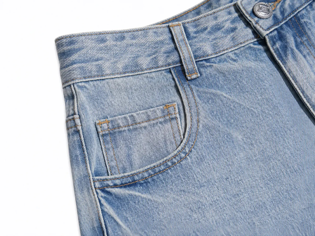 Close-up detail of a pair of light-wash blue denim jeans showing the back pocket, belt loop, and button on a white background. TCH Rhinestone Teddy Bear Star Wide-Leg Jeans