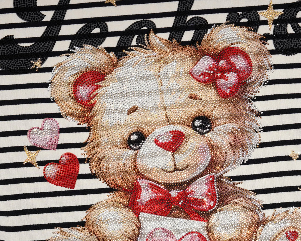 Close-up of a teddy bear design on a black-and-white striped fabric, featuring a beige bear with red bow and heart details, plus small pink and red hearts. TCH Rhinestone Teddy Bear Striped Tie-Side T-Shirt