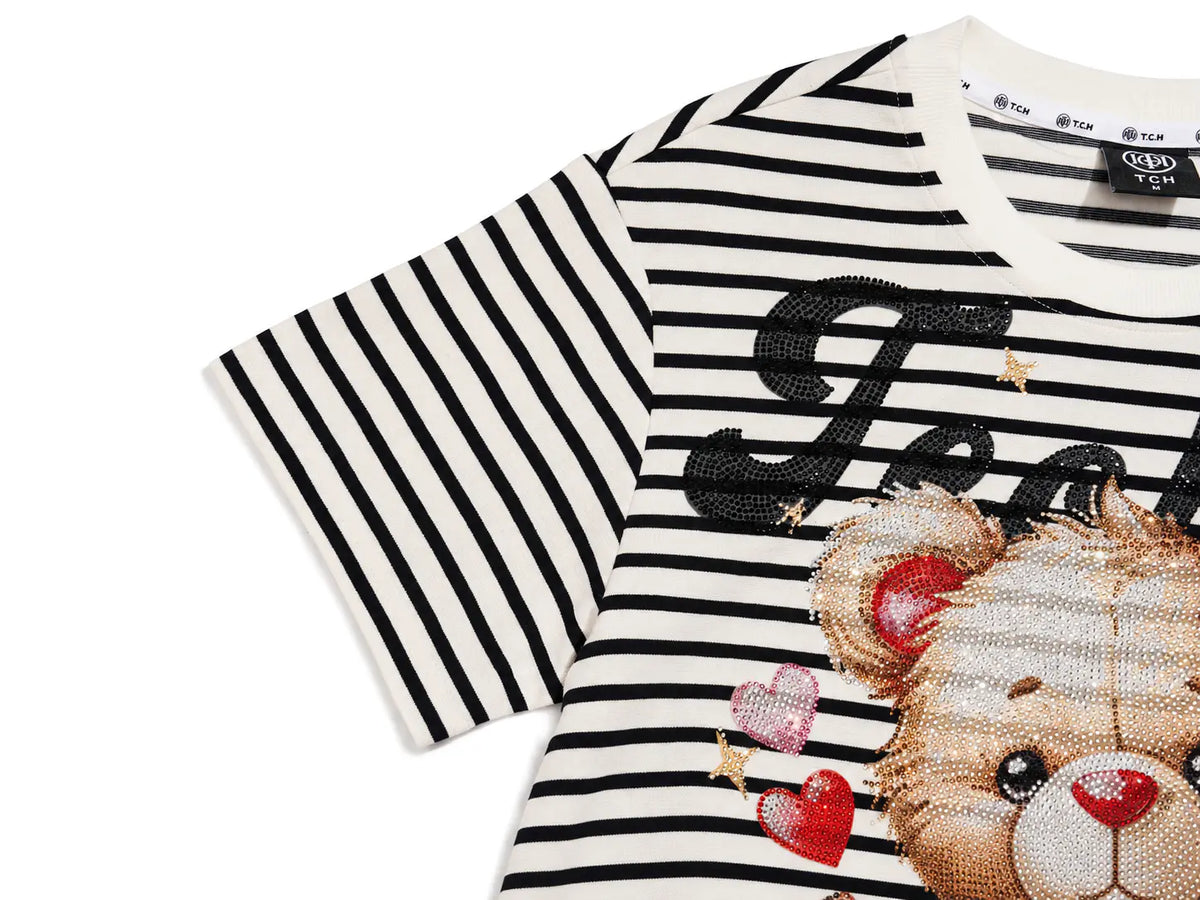 A close-up of a children's short-sleeve top with black and white horizontal stripes, featuring a sequined teddy bear graphic and black sequined lettering on the front, set against a plain white background. TCH Rhinestone Teddy Bear Striped Tie-Side T-Shirt