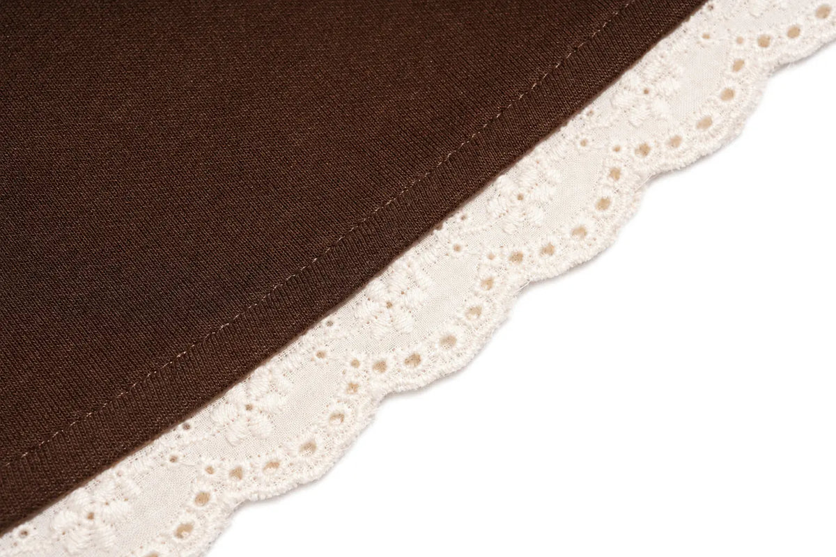 Close-up of a dark brown fabric item with a decorative off-white lace trim along one edge, shown on a white background. TCH Rhinestone Teddy Bear Techno Sweatshirt Dress