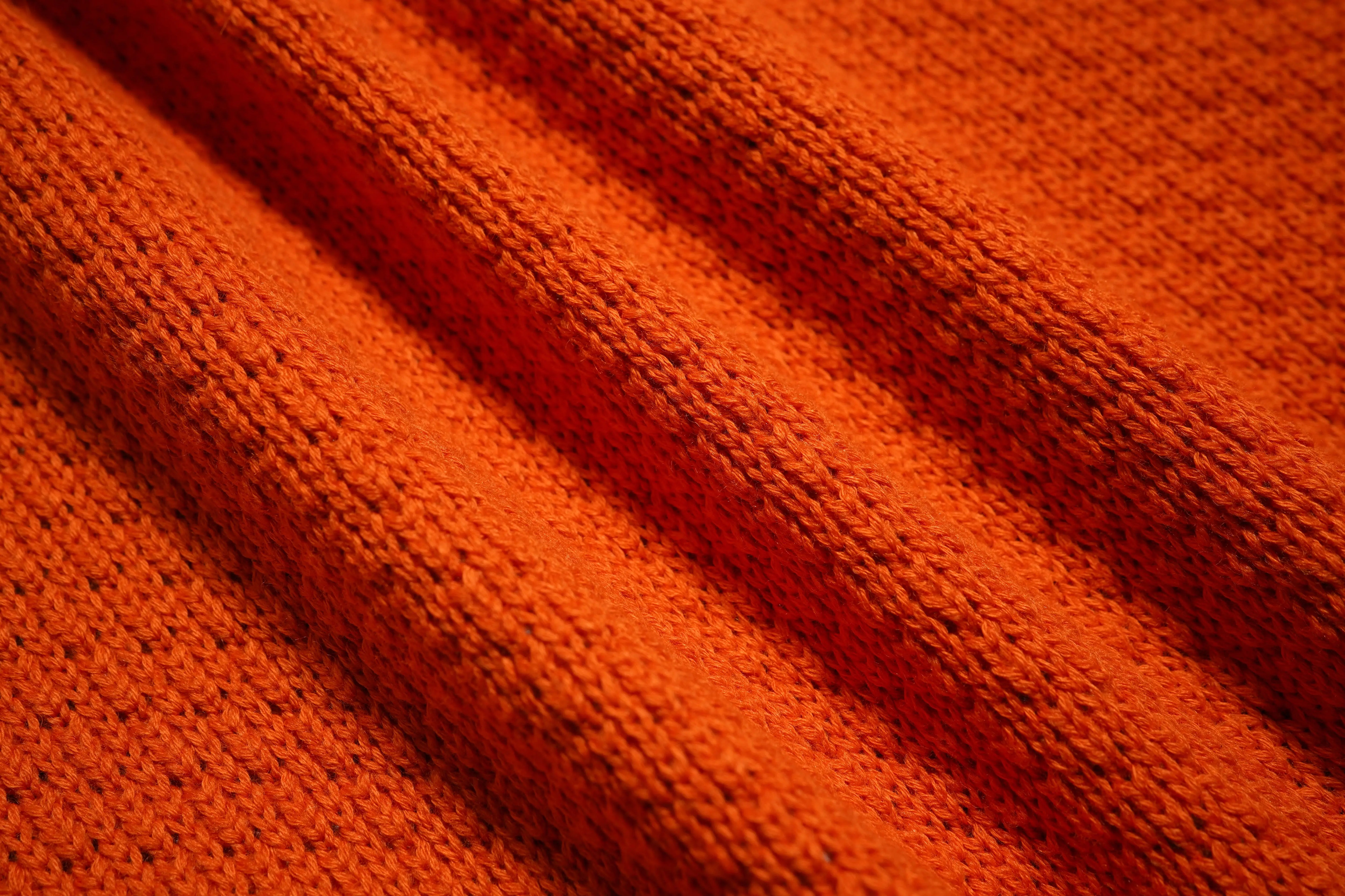 Close-up of orange fabric with a textured pattern, TCH Rhinestone Unicorn Orange Hoodie