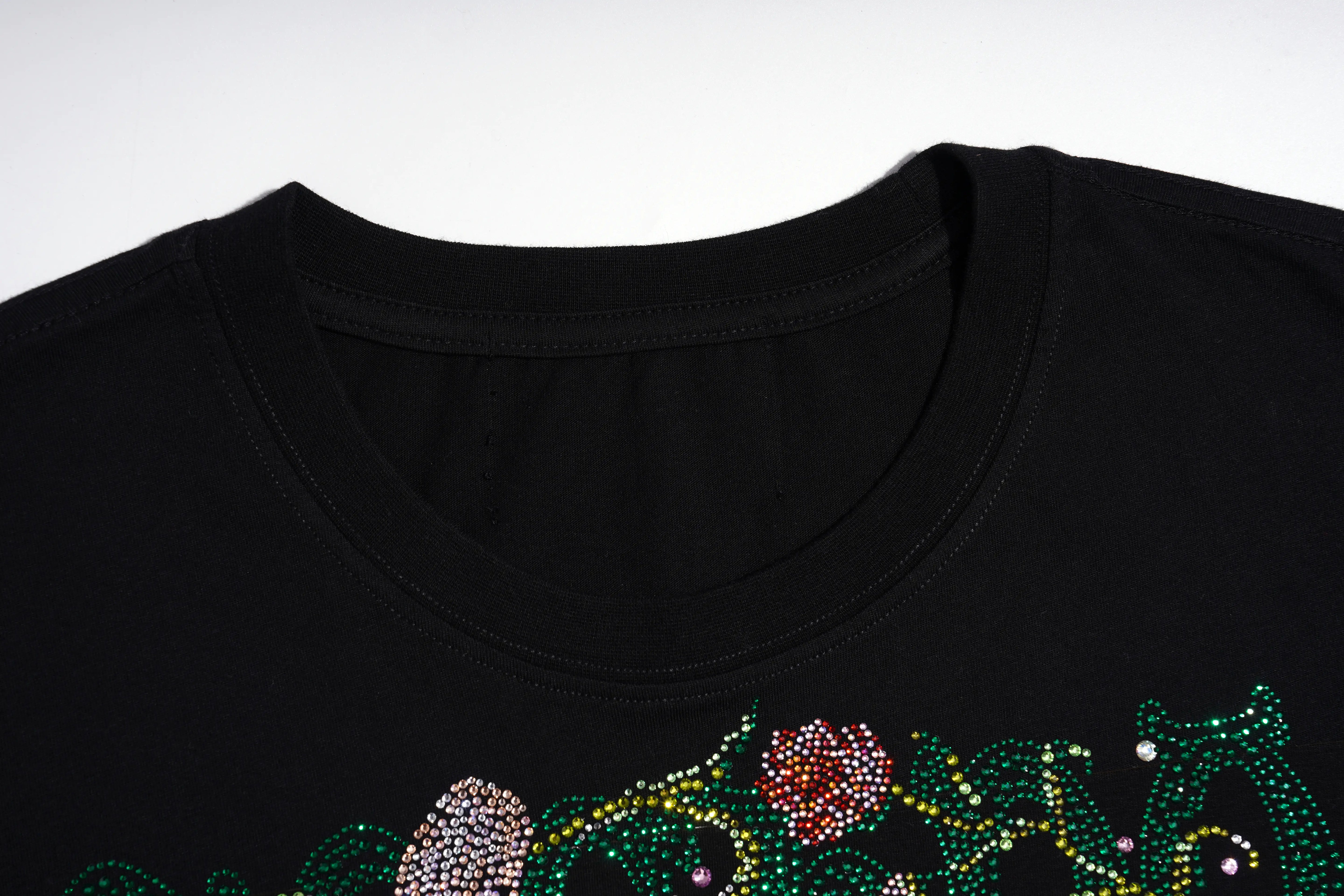Close-up of a black crewneck t-shirt featuring a rhinestone-embellished floral pattern in green, pink, and silver along the lower hem. TCH Rhinestone Vintage Floral Artwork Graphic Black T-Shirt