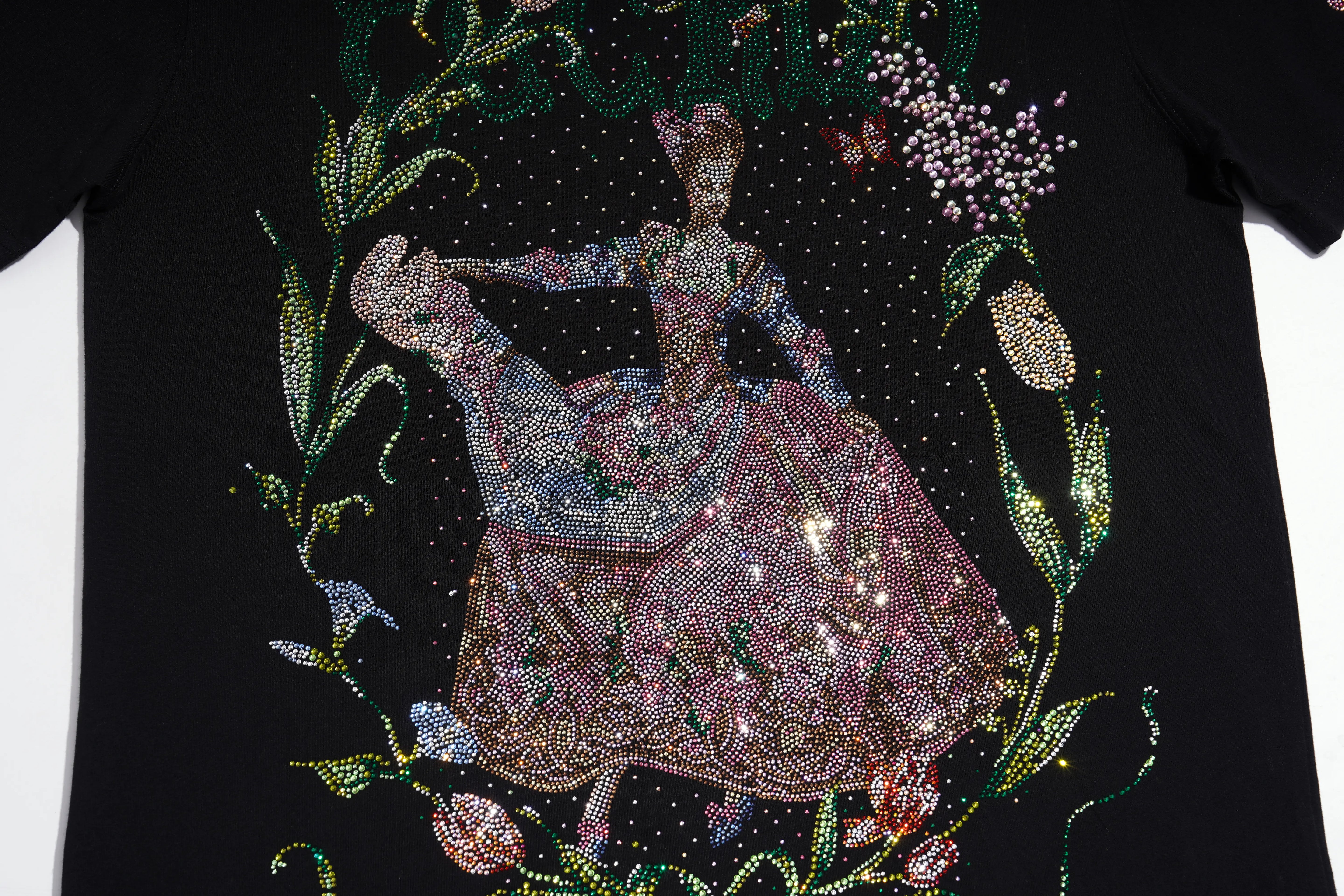 A close-up of a black t-shirt featuring an intricate, rhinestone-embellished graphic of a dancing ballerina in a pink and blue gown, surrounded by floral and vine motifs on a white background. TCH Rhinestone Vintage Floral Artwork Graphic Black T-Shirt