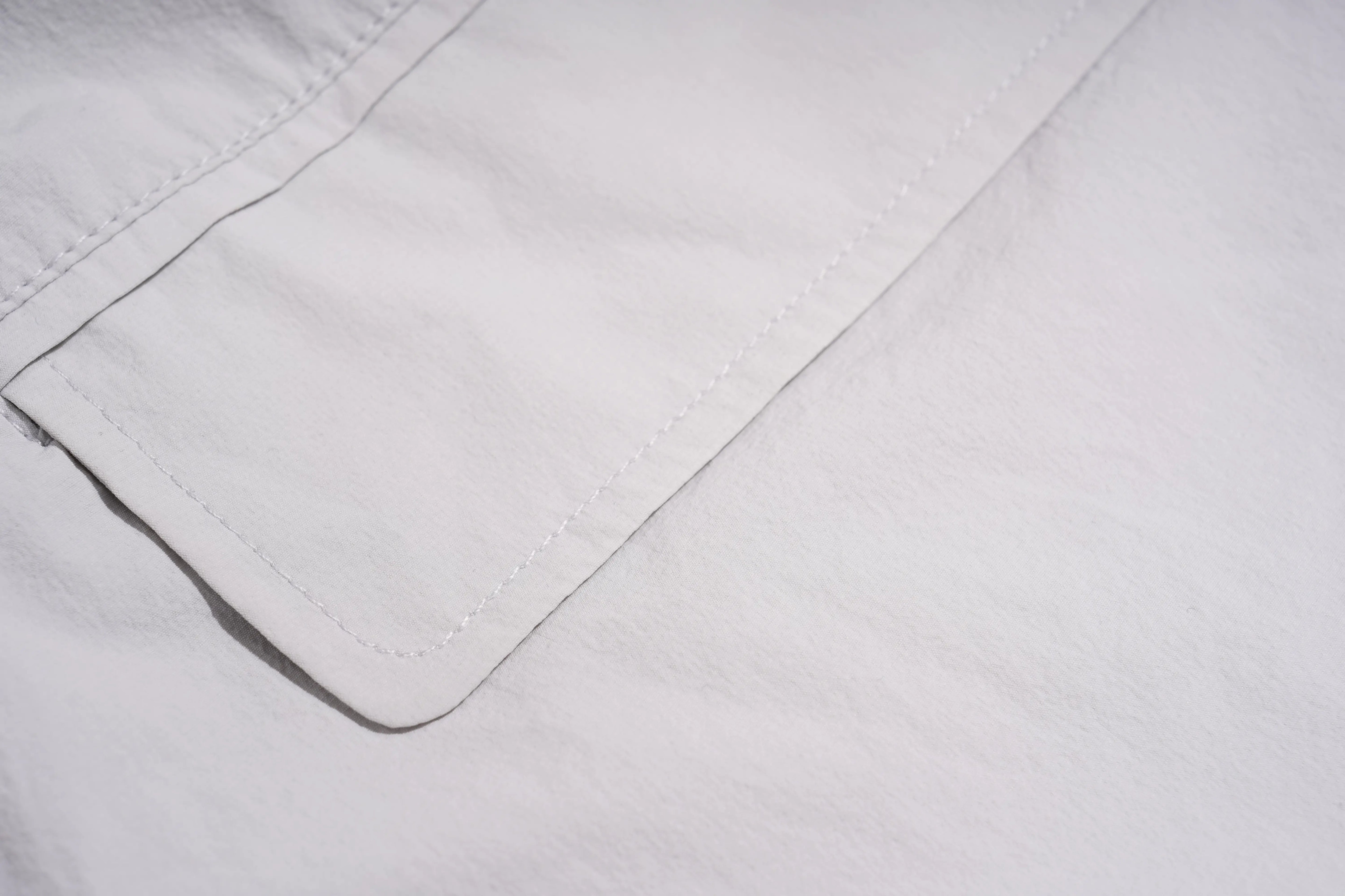 Close-up of a white fabric surface with a stitched pocket or flap detail. TCH Rhinestone Wing Active 3-Piece Tracksuit Set