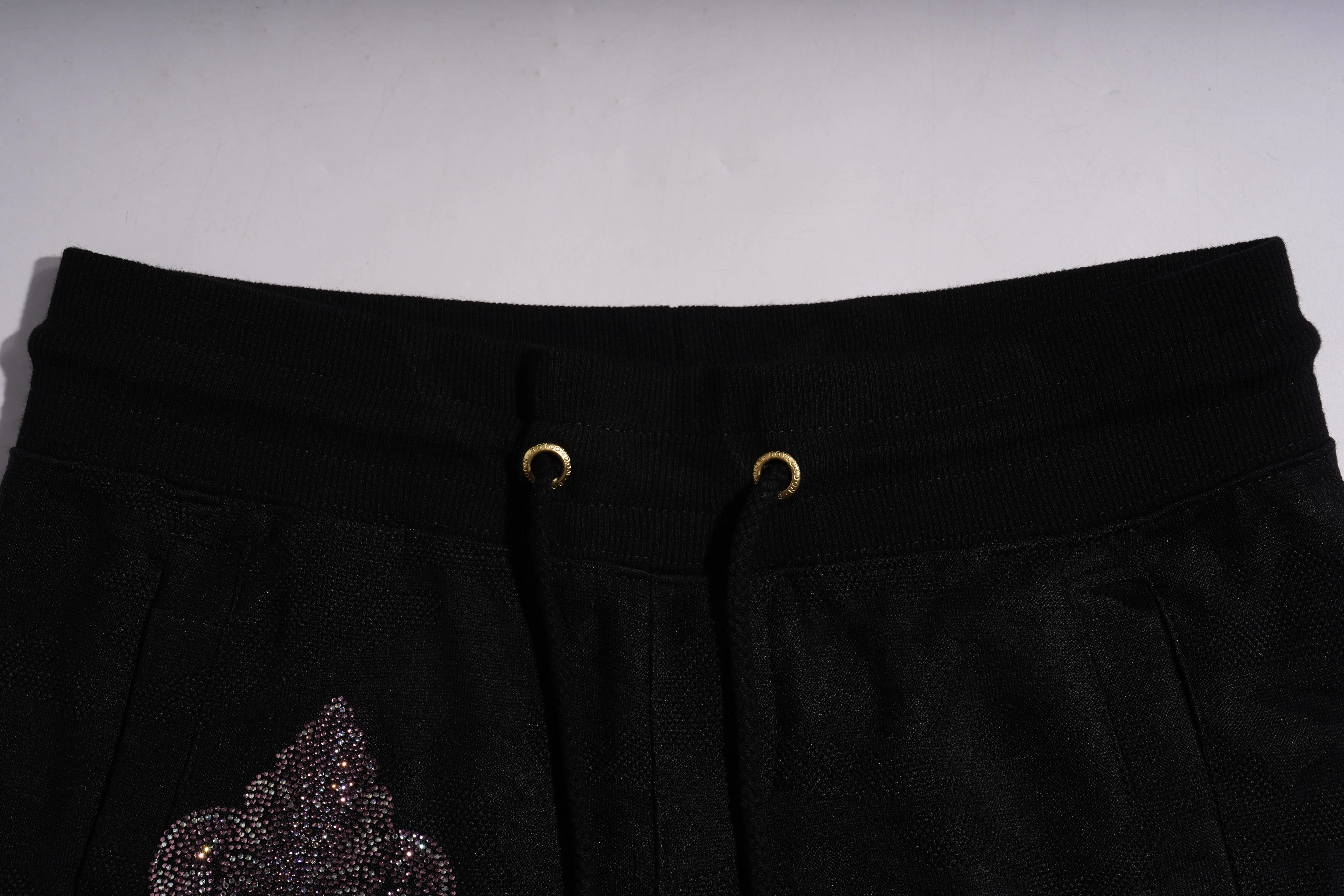 Black pants with decorative embellishment on a light gray background, TCH Rhinestone Wing Camo Jogger Pants