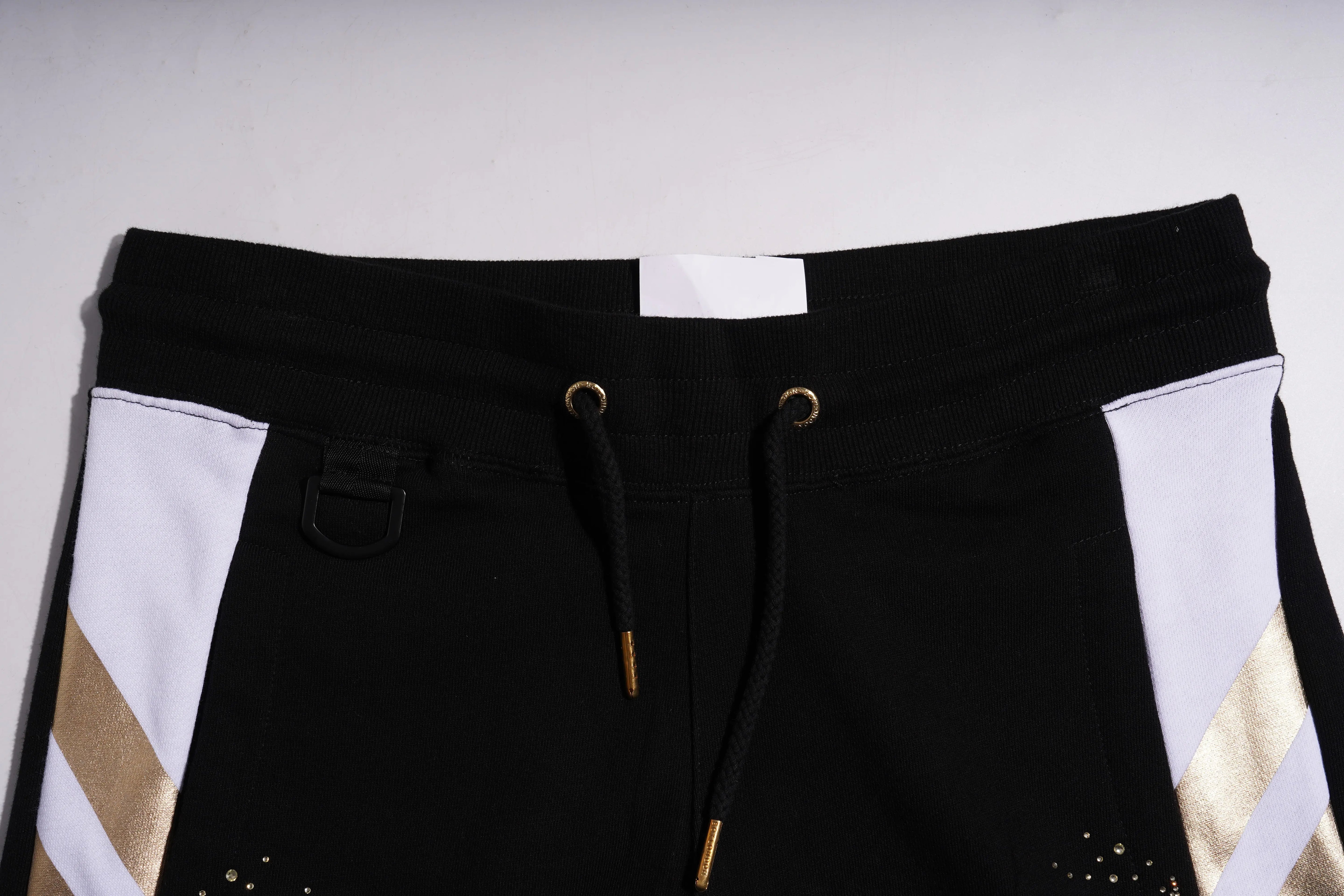 Black pants with white and gold accents on a light gray background, TCH Rhinestone Wing Techno Jogger Pants