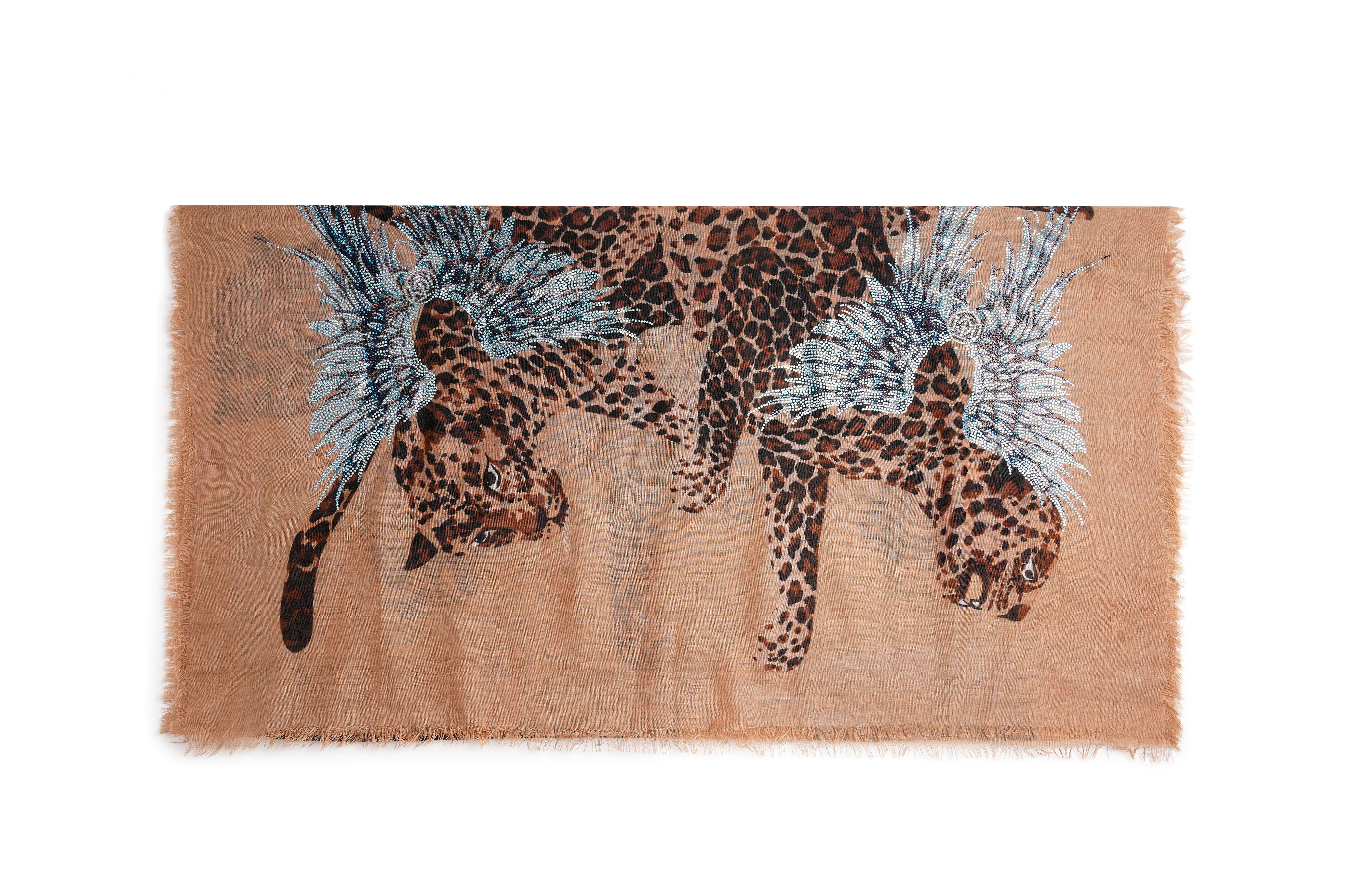 A rectangular scarf with fringed edges, featuring a tan and brown leopard print overlaid with two large blue and white feather motifs, shown on a plain white background. TCH Rhinestone Winged Leopard Lightweight Fashion Scarf