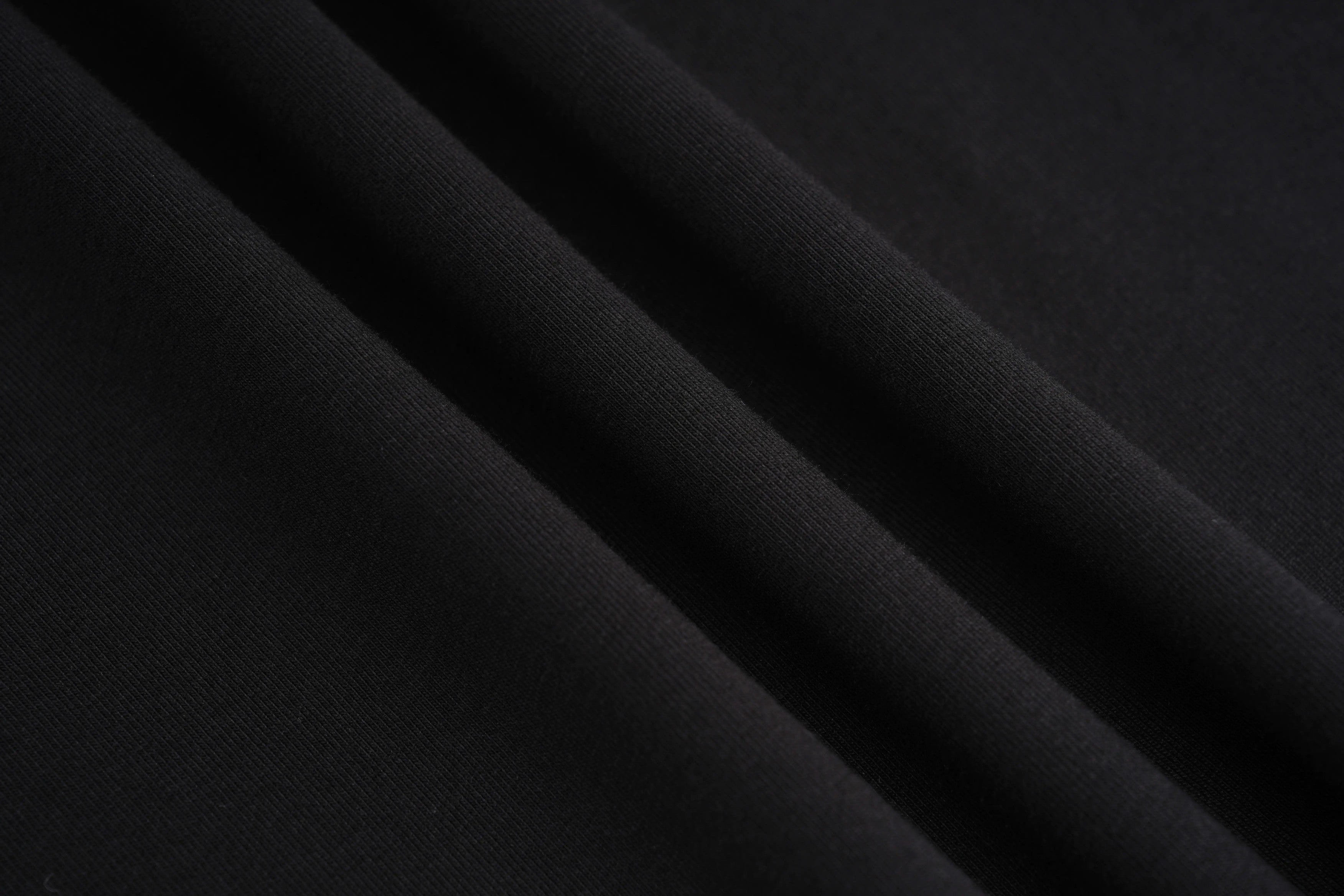 Close-up of black fabric with folds, TCH Rhinestone Wings Logo Black Graphic T-Shirt