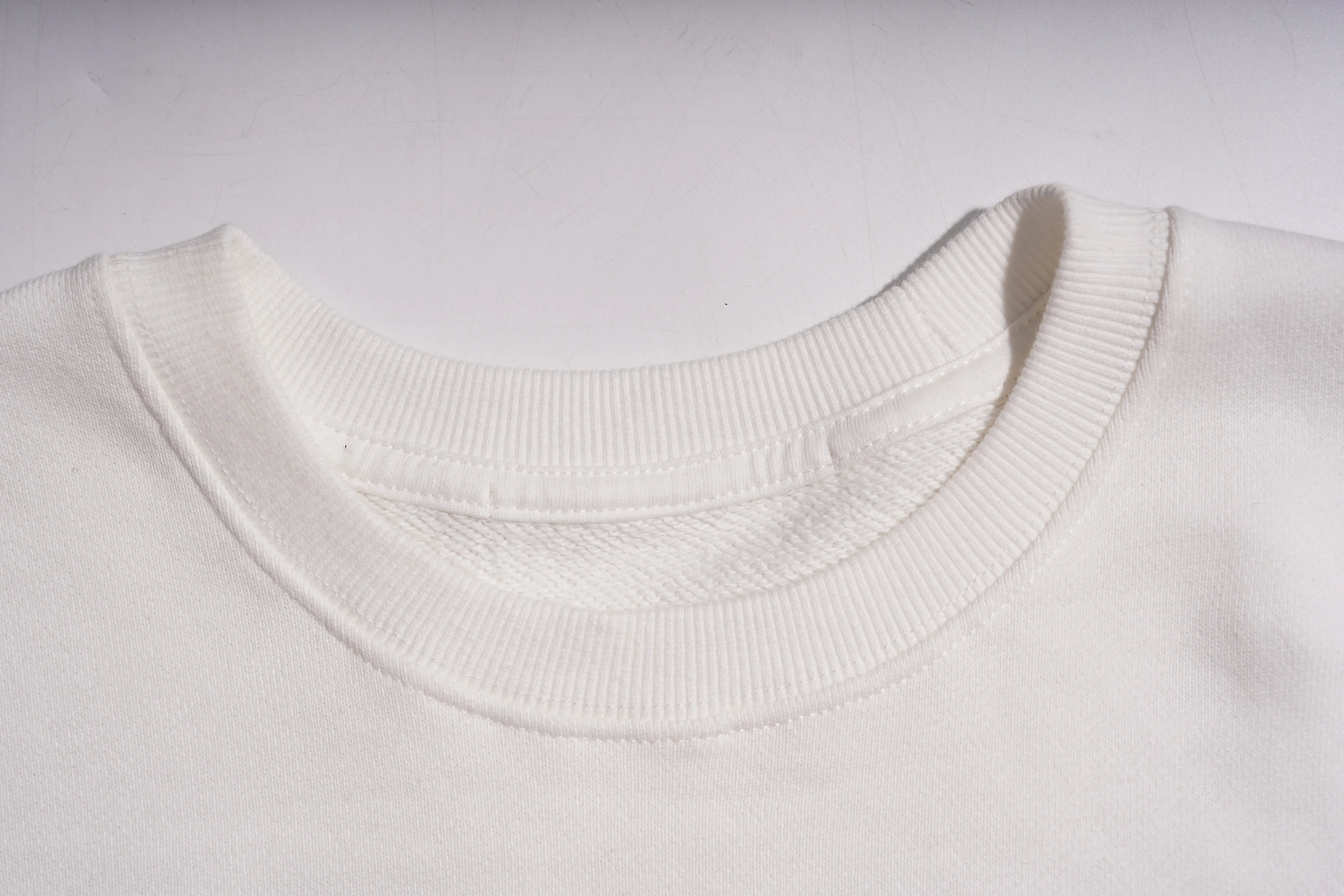 Close-up of a white sweater collar on a light gray background, TCH Rhinestone Winter Lamb Sweatshirt