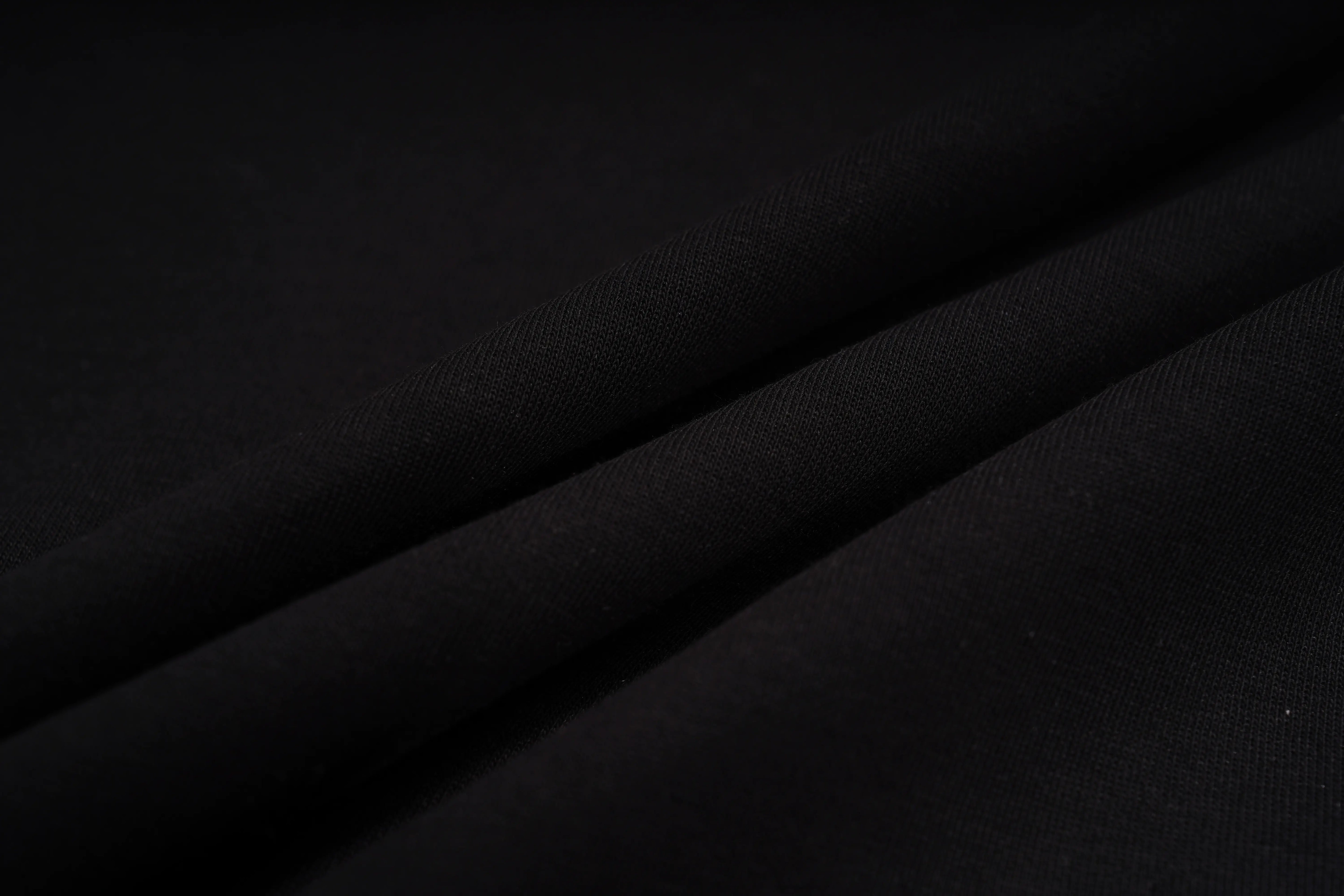 A close-up of draped black fabric with soft folds and a smooth matte texture. TCH Sagittarius Celestial Graphic Oversized T-Shirt