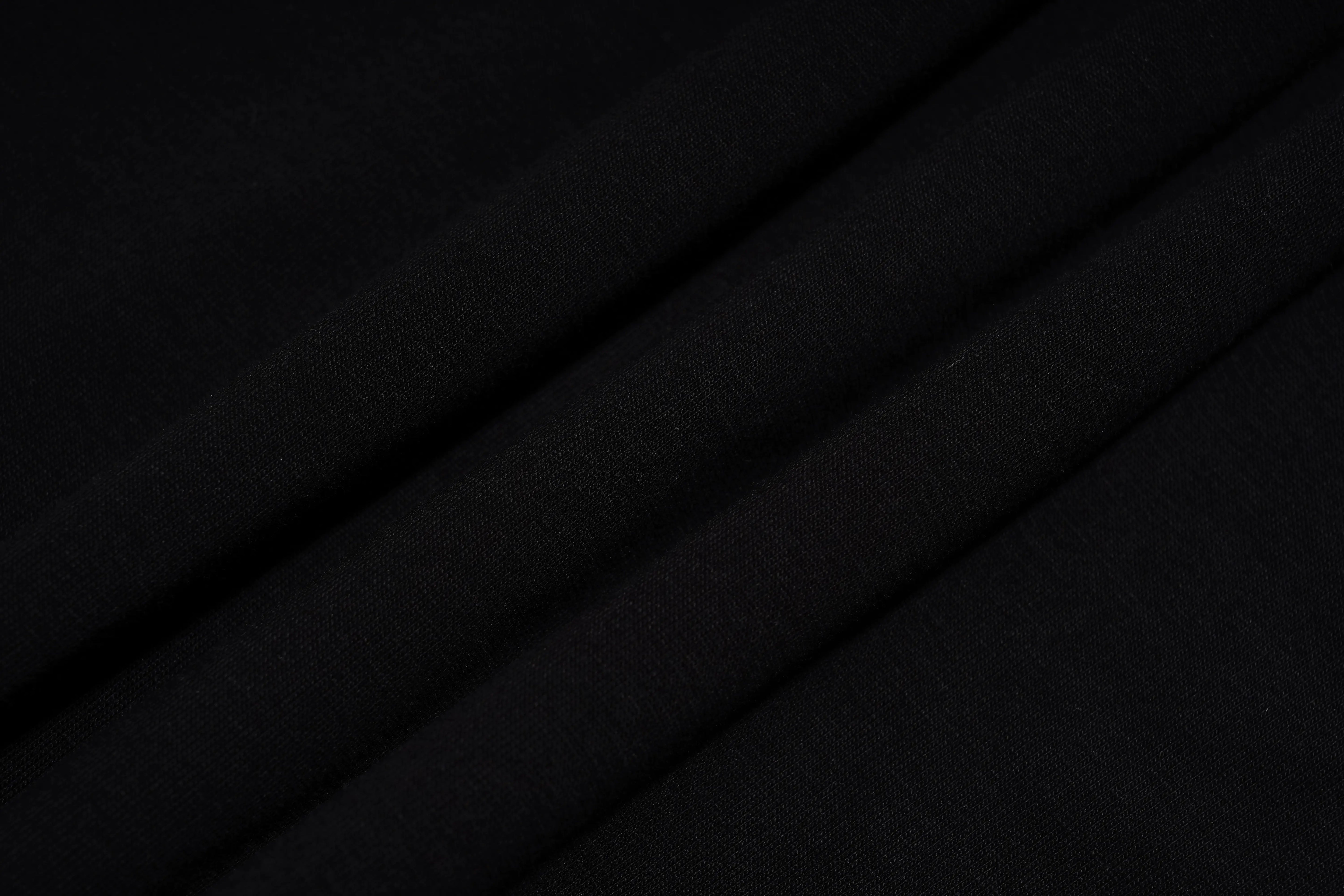 A close-up of draped black fabric with soft diagonal folds showing a fine woven texture. TCH Silver Wing Techno Oversized Graphic T-Shirt
