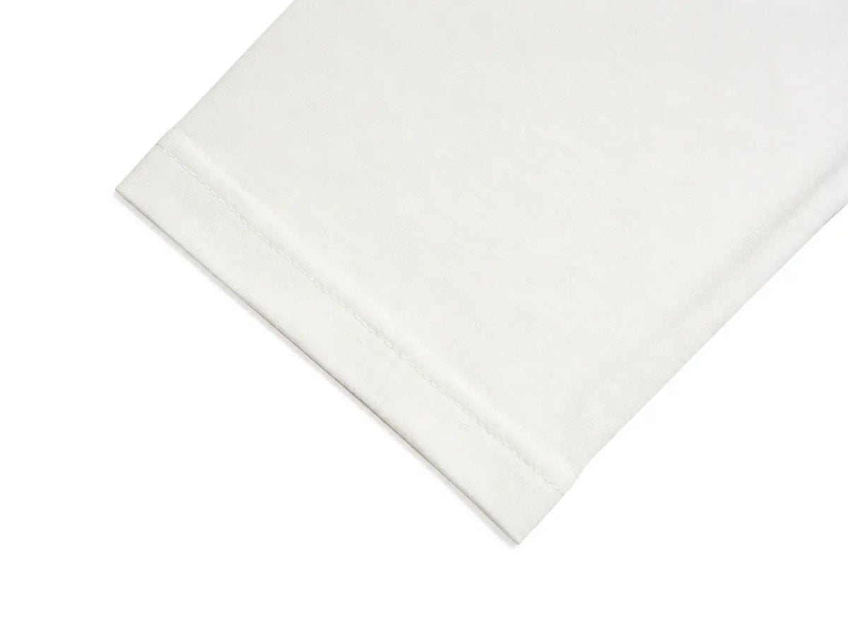 A close-up of a white folded fabric item, showing a clean stitched hem on a white background. TCH Small Bear Angel Wings Rhinestone Graphic White Long Sleeve T-Shirt
