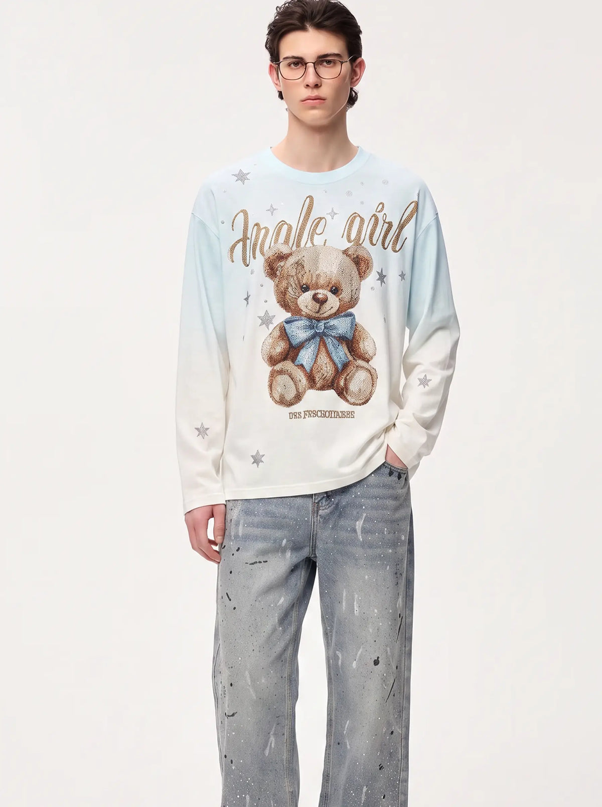 A model wearing a light blue and white long-sleeve graphic sweatshirt with a teddy bear print and the text 'angel girl', paired with light-wash jeans, against a plain white studio background. TCH Small Bear Angel Wings Rhinestone Graphic White Long Sleeve T-Shirt