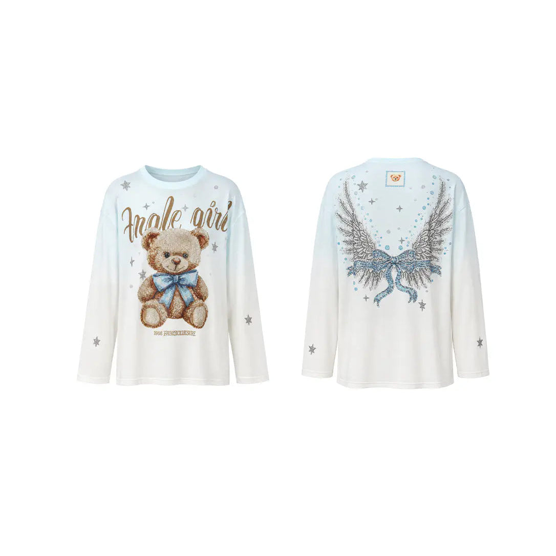 Close-up of a pink and white beaded bow design with gold-toned rhinestone outlines and small pastel blue floral accents on a white background. TCH Small Bear Angel Wings Rhinestone Graphic White Long Sleeve T-Shirt