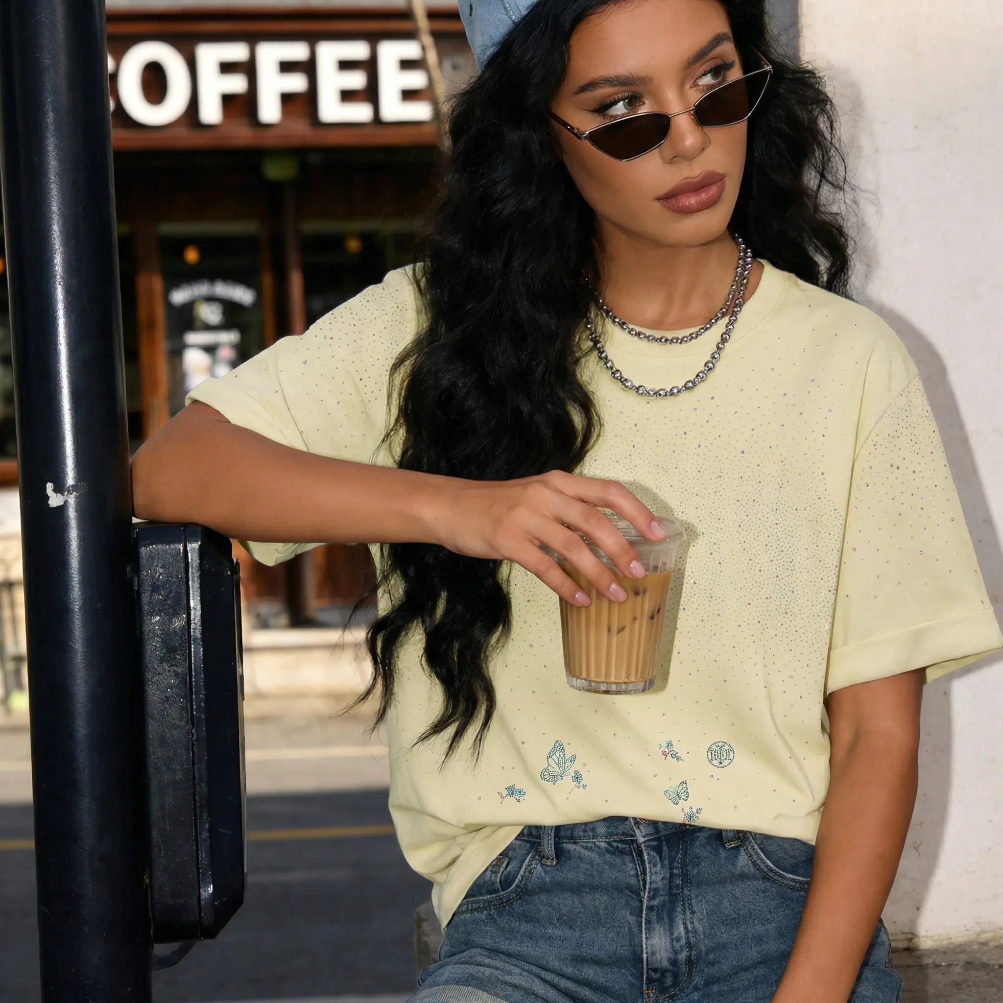 Woman holding a coffee cup in an urban setting with a coffee shop in the background, TCH Starry Gradient Rhinestone Butterfly T-Shirt