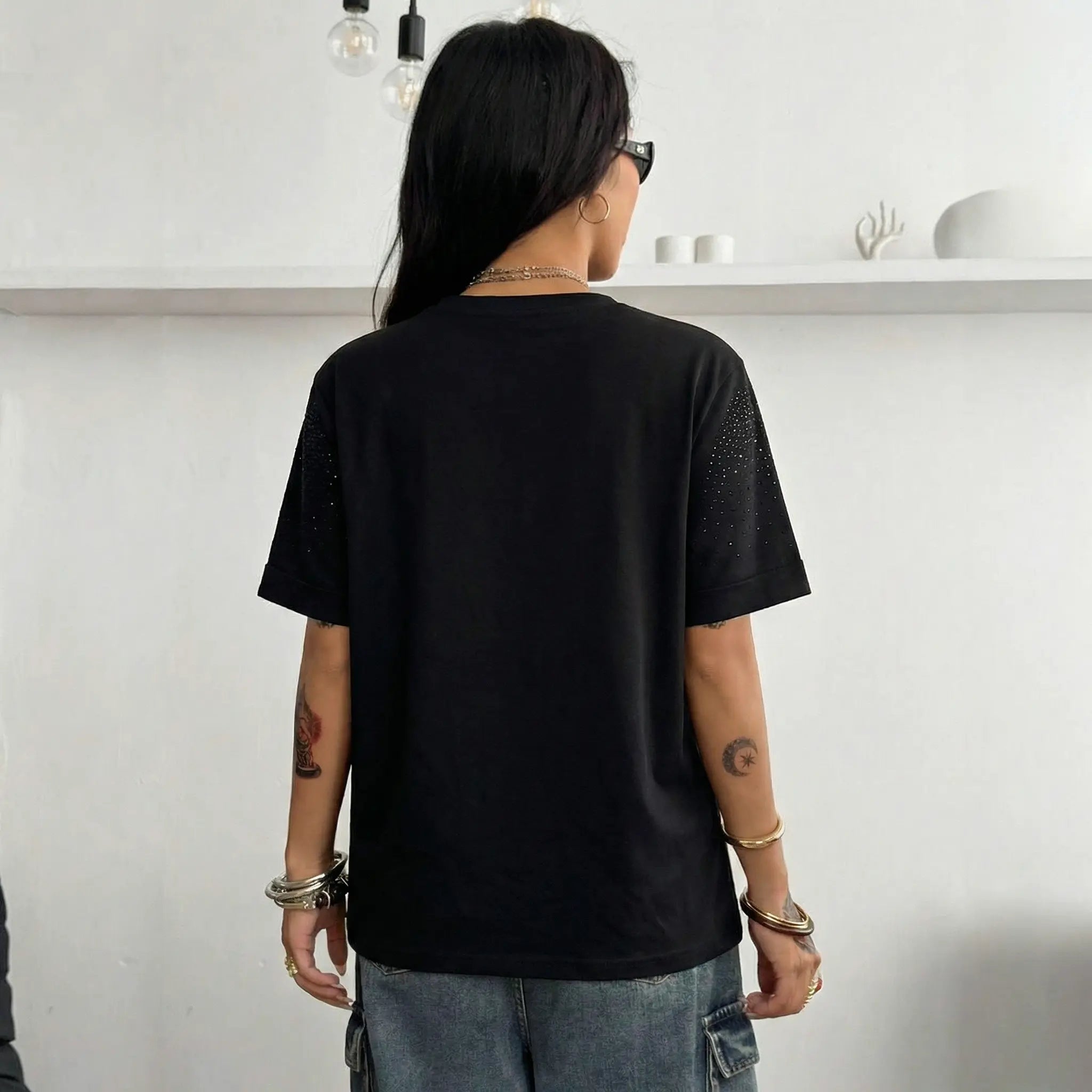 Person wearing a black t-shirt with visible tattoos on arms, standing against a white wall. TCH Starry Gradient Rhinestone Butterfly T-Shirt
