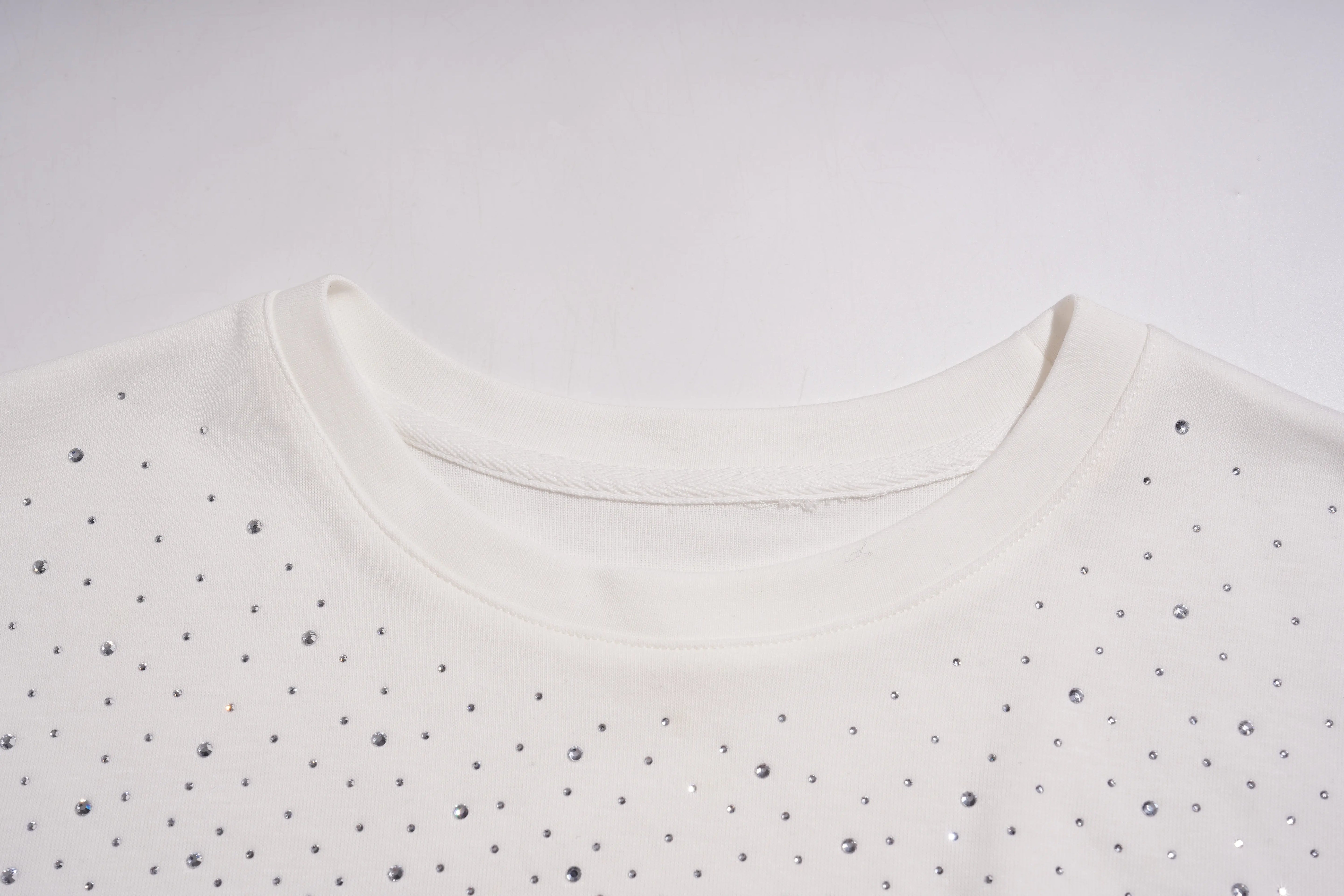 Close-up of a white top with small black embellishments on a light gray background, TCH Starry Gradient Rhinestone Butterfly T-Shirt